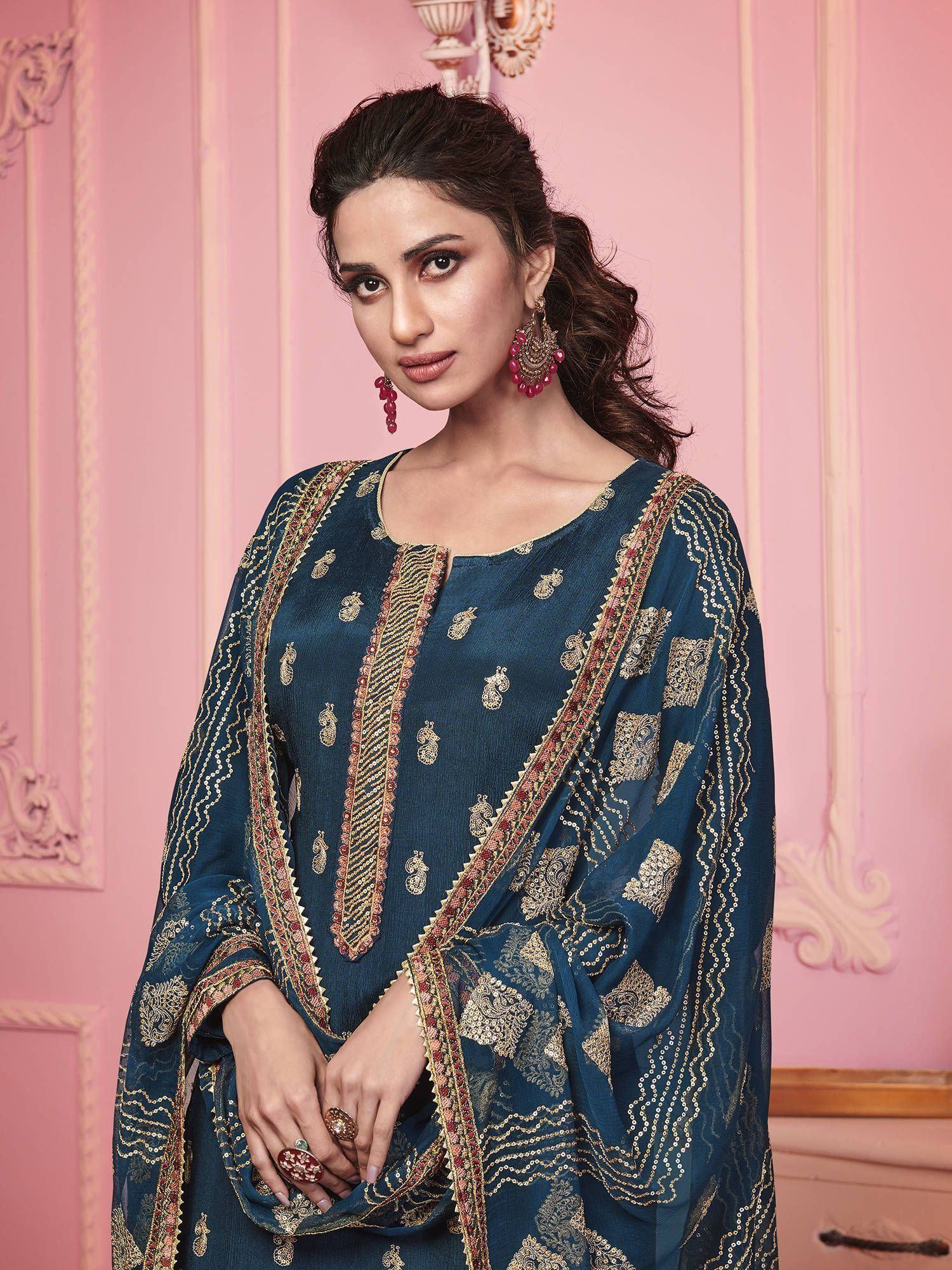 Woman wearing navy blue embroidered ethnic salwar kameez with gold detailing, pink earrings