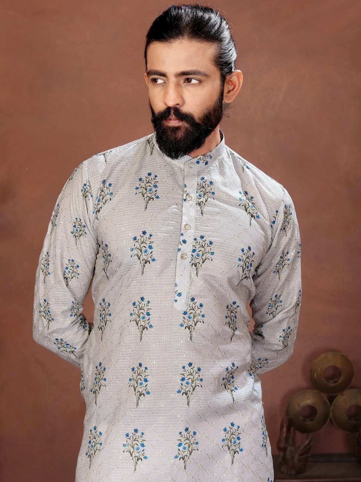 Man wearing a light grey embroidered ethnic kurta with blue floral patterns