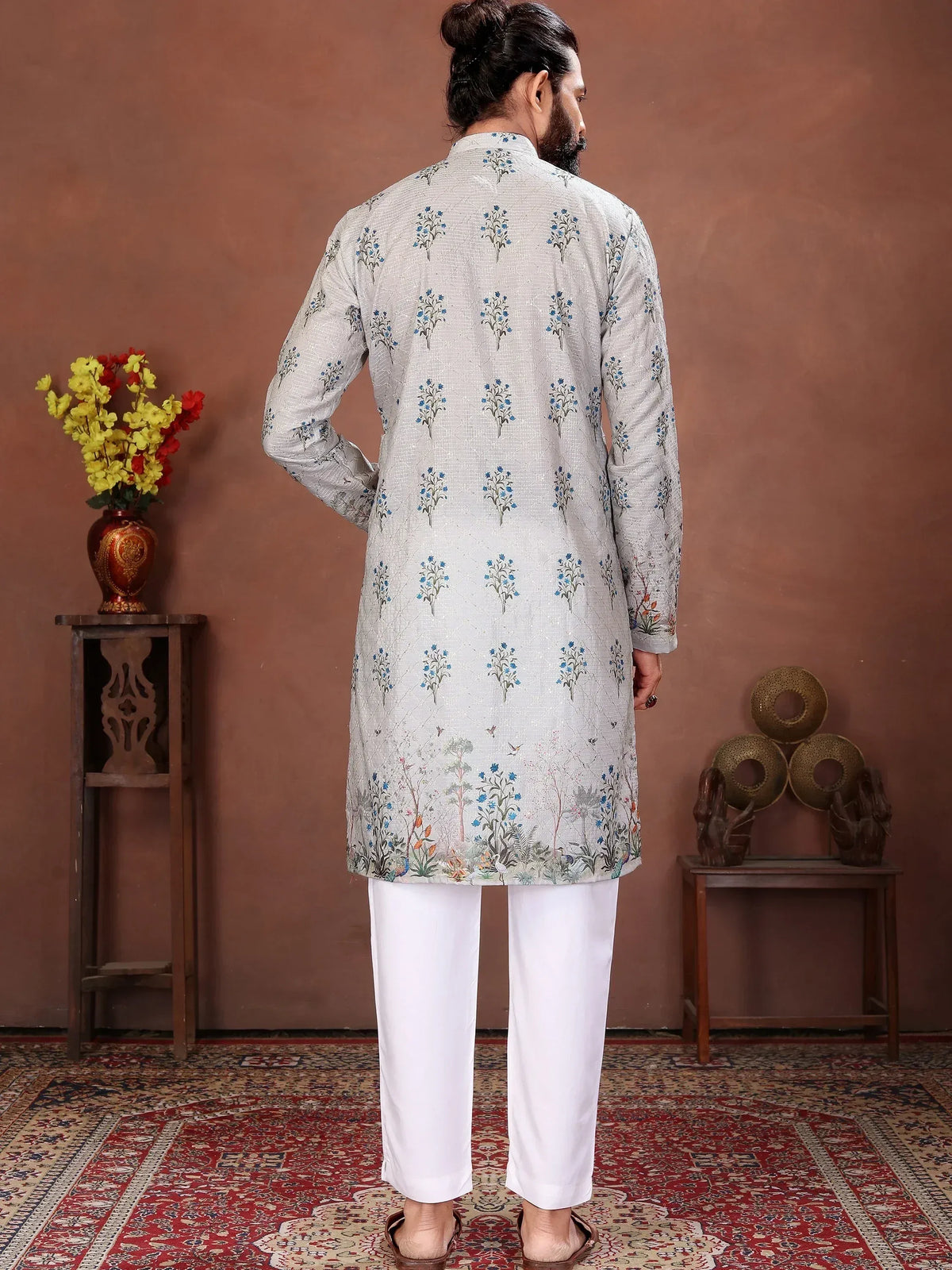 Back view of a man wearing a grey floral print ethnic kurta and white trousers.