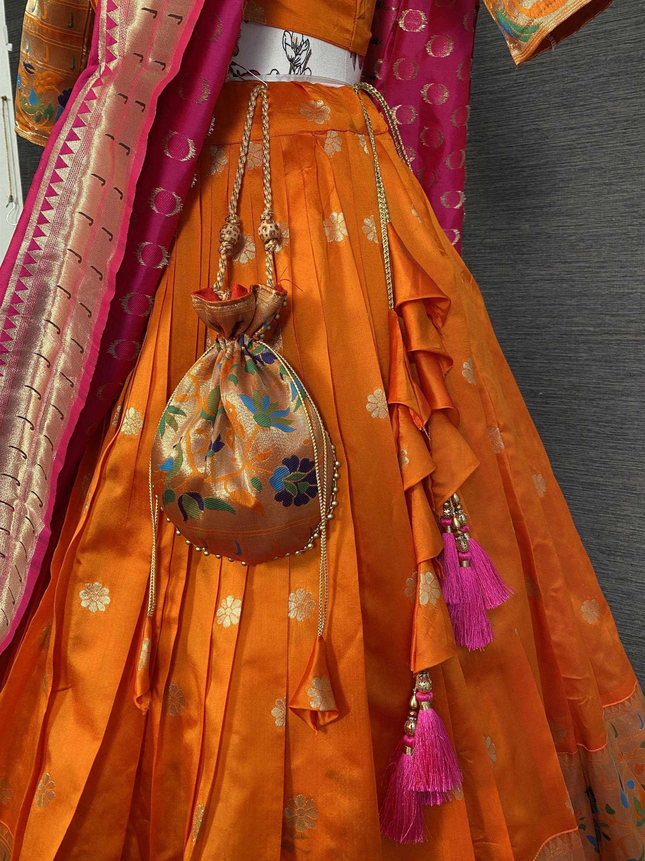 Orange floral lehenga with pink tassels and embroidered potli bag