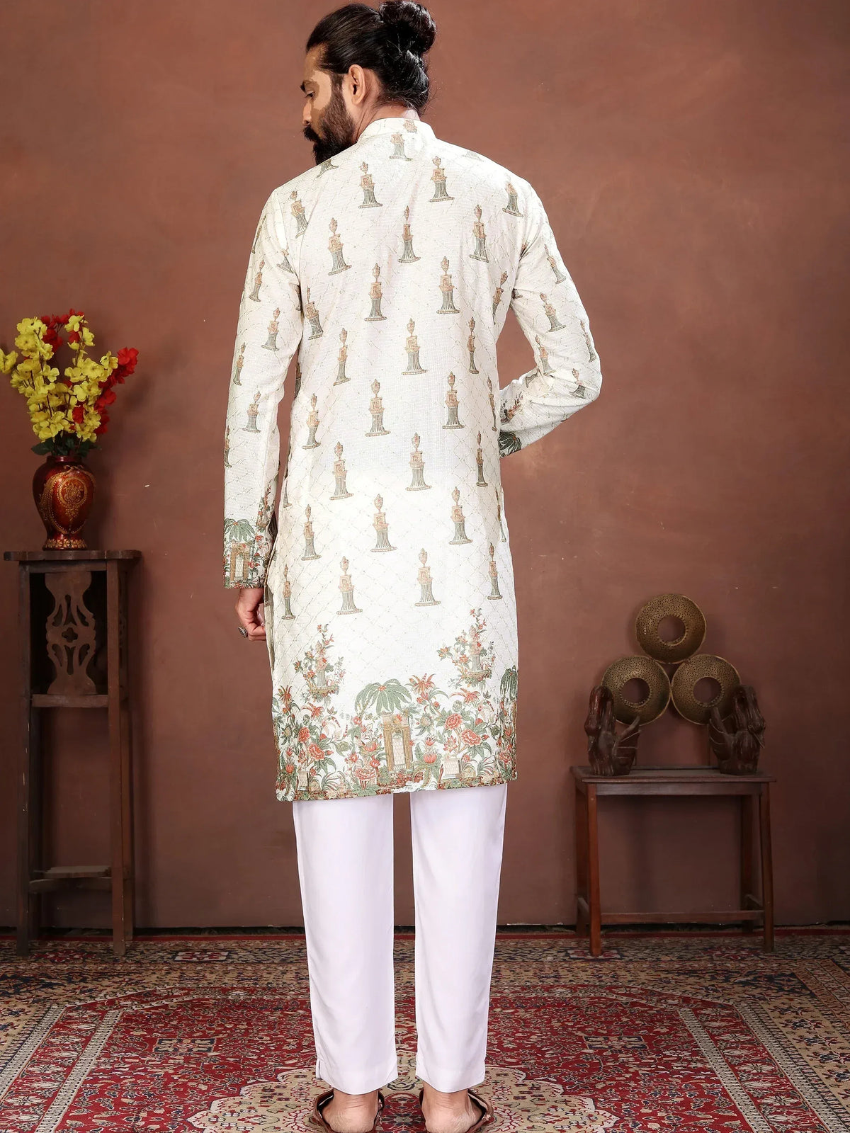 Man wearing a white printed designer kurta with floral border and white trousers