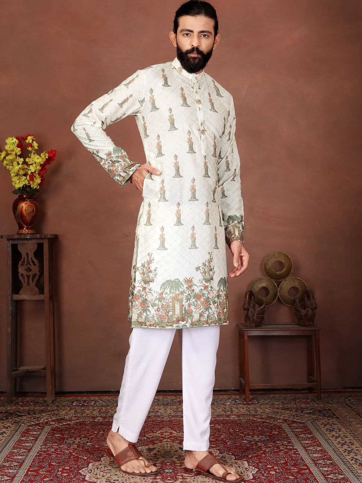Man in a printed white ethnic kurta and white pajama standing on a red carpet.