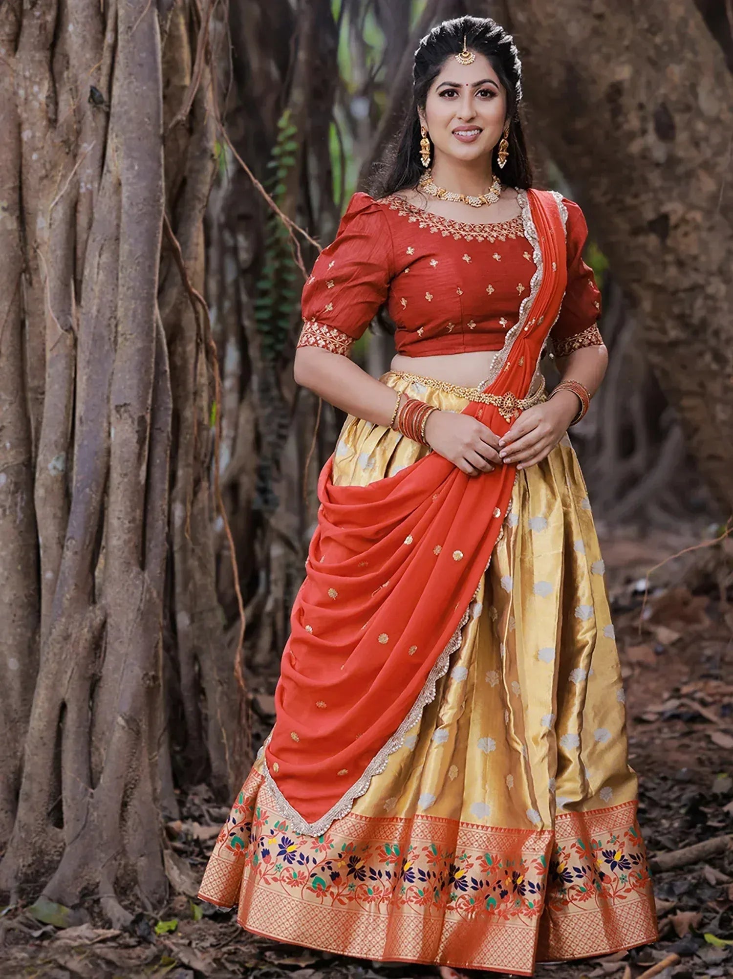 Woman in red and gold designer lehenga choli with floral border, perfect for Indian ethnic wear occasions