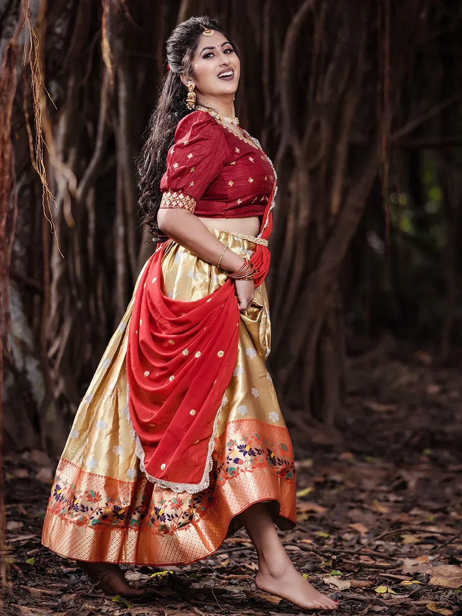 Woman in red and gold designer lehenga choli with floral border, perfect for Indian ethnic occasions