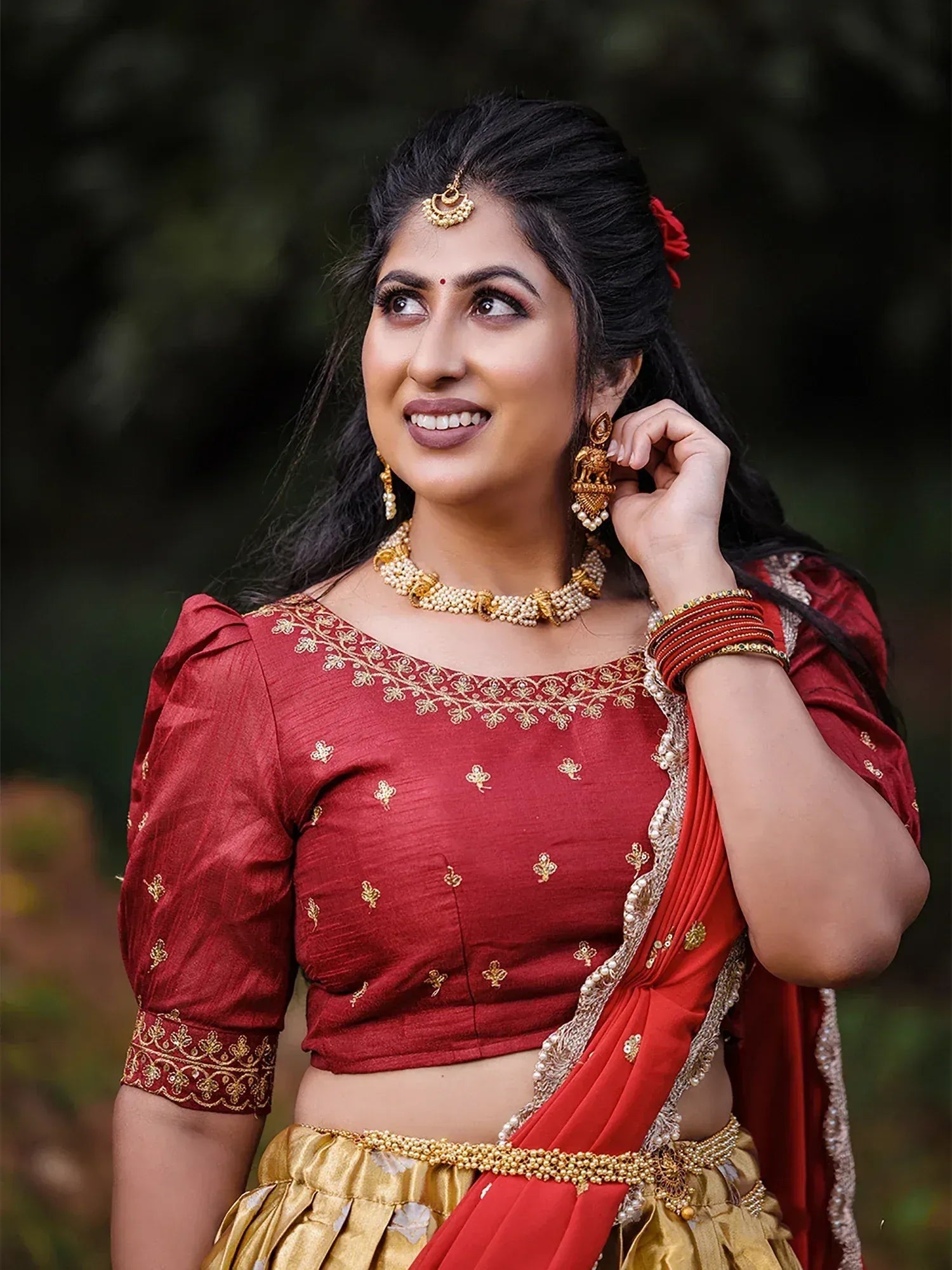 Woman in red and gold ethnic lehenga choli with gold jewelry, perfect for Indian weddings or festivals
