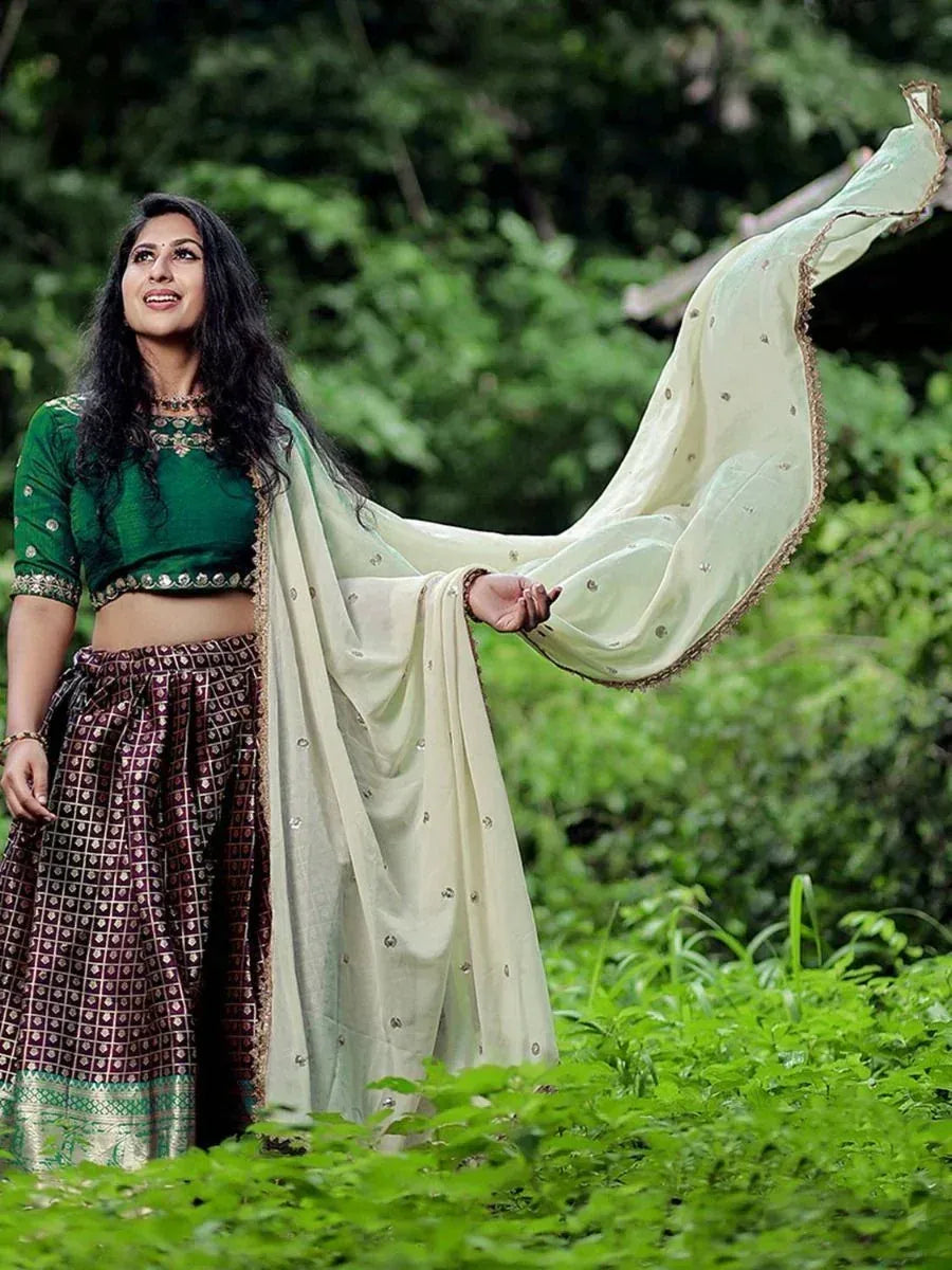 Woman in green blouse and patterned lehenga with flowing dupatta, ethnic Indian wear