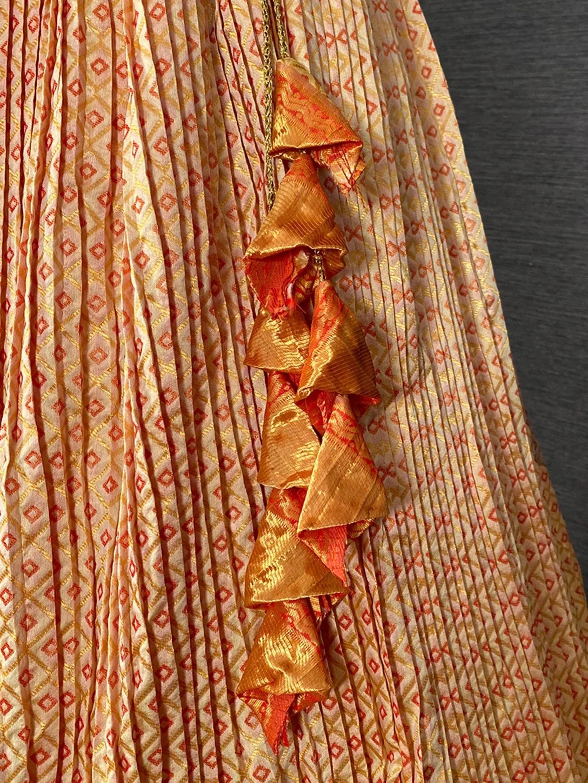 Pleated ethnic gown with geometric print and gold-orange ruffle detailing, perfect for Indian festive wear.