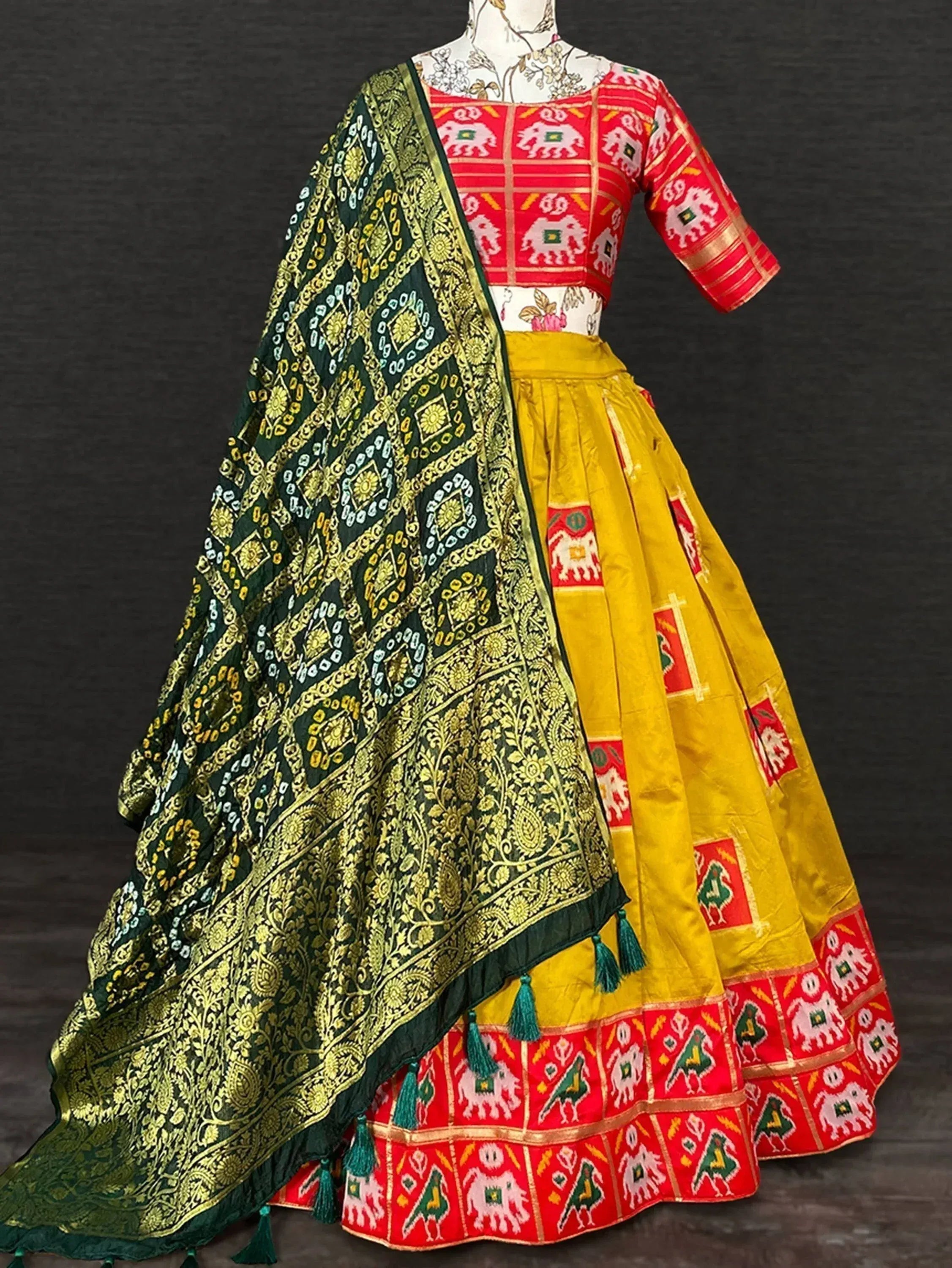 Red and yellow ethnic lehenga choli with elephant print, paired with green embroidered dupatta for festive wear