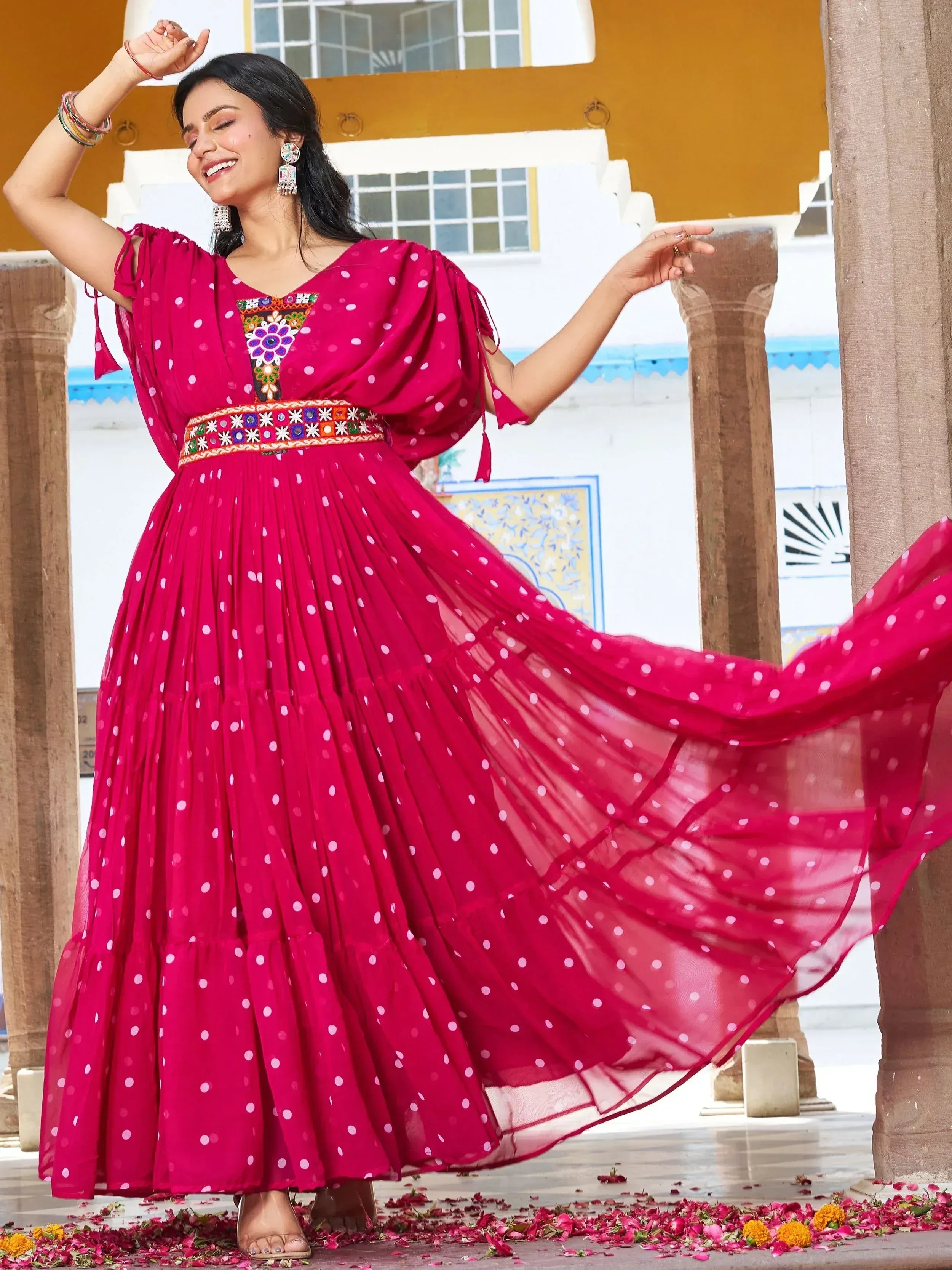 Woman in vibrant pink polka dot ethnic gown with embroidery, dancing gracefully outdoors