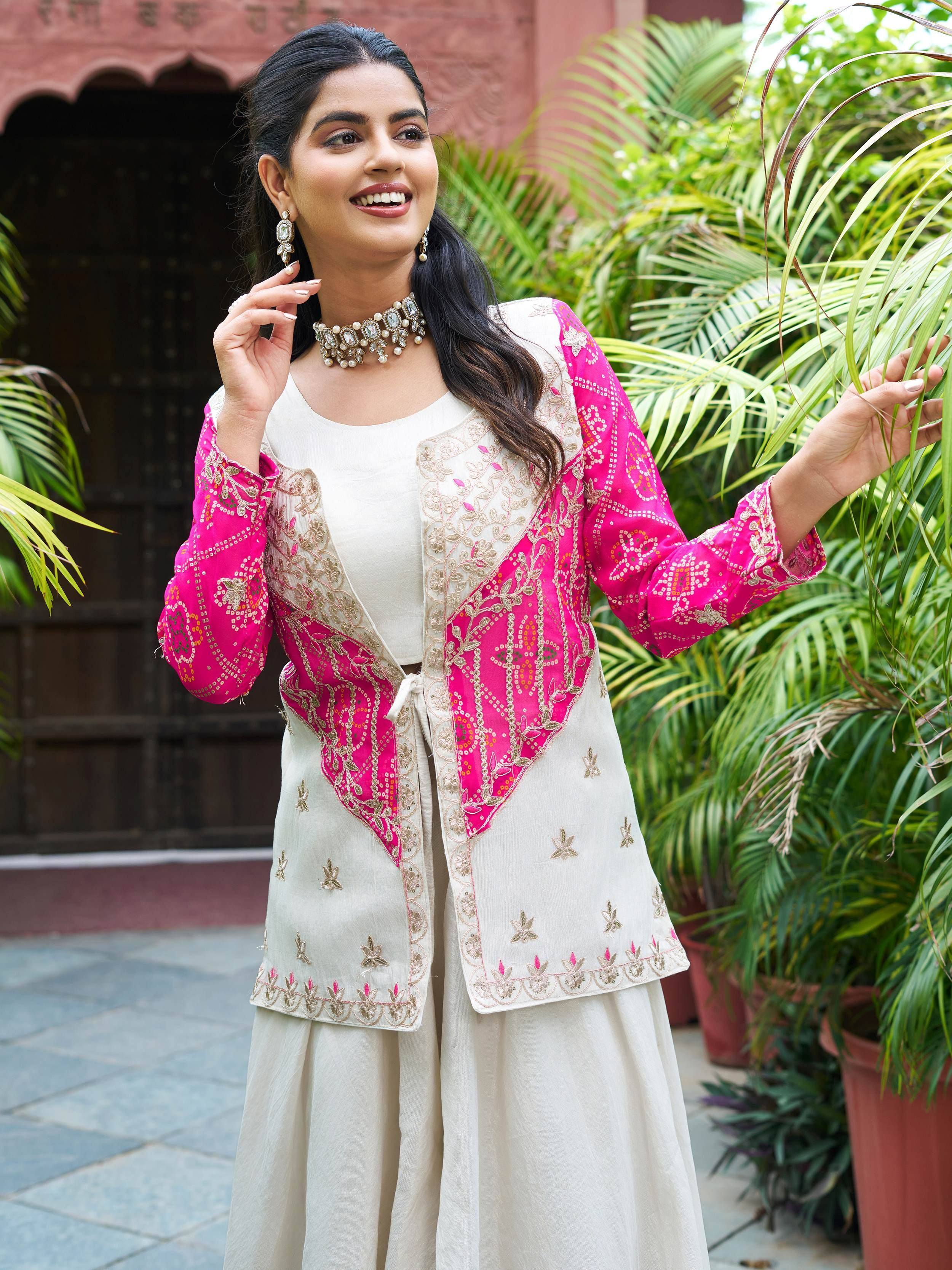 Woman in embroidered pink and cream Indian ethnic wear with gold detailing, styled with statement jewelry outdoors
