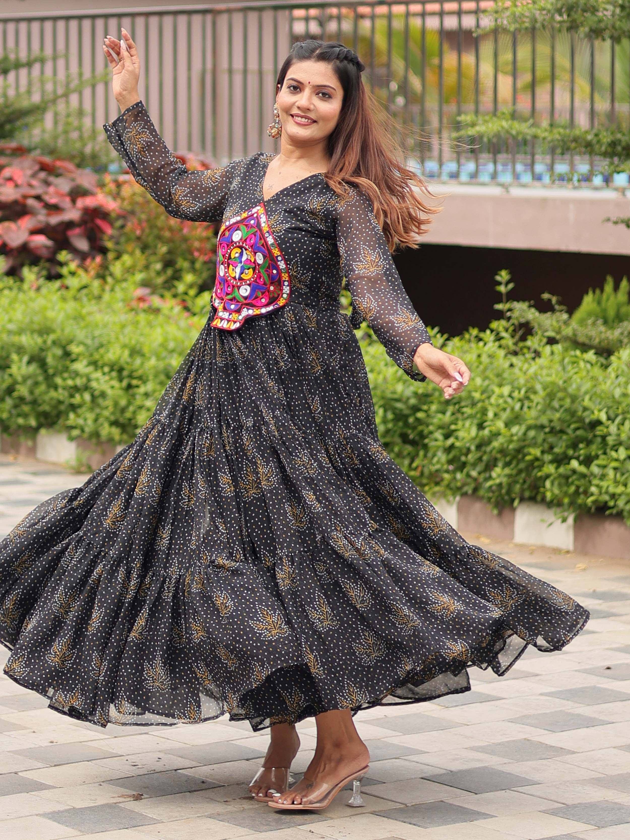 Woman in black ethnic gown with colorful embroidery, twirling outdoors