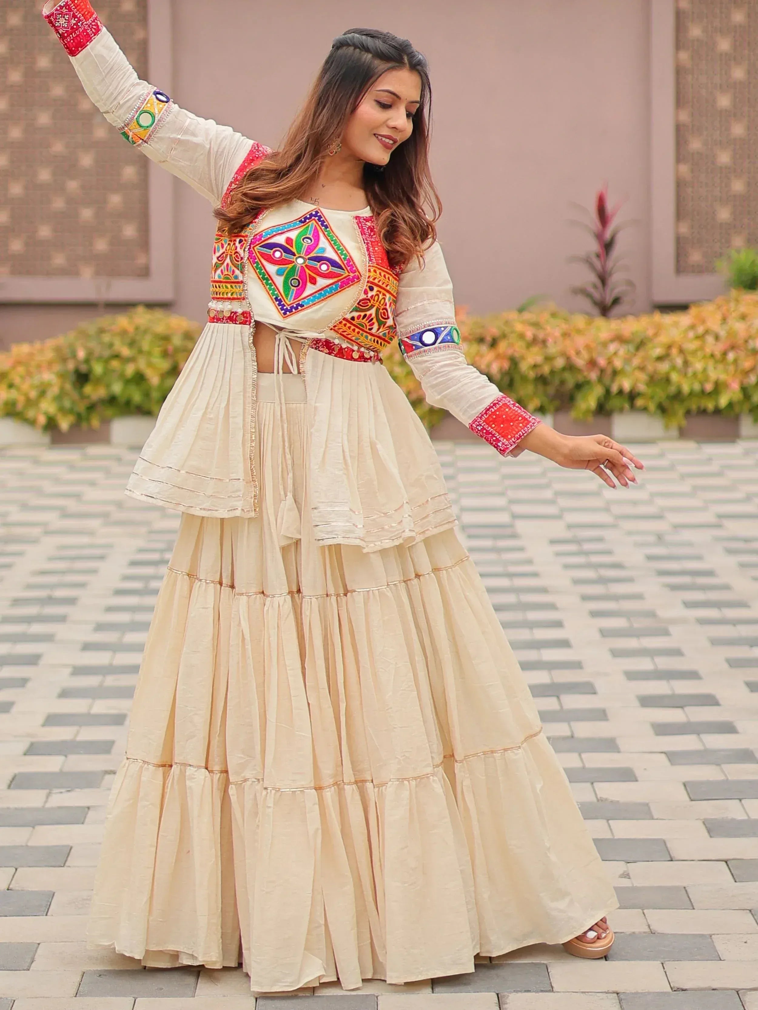 Woman in cream embroidered lehenga choli with colorful mirror work, perfect for Indian ethnic wear