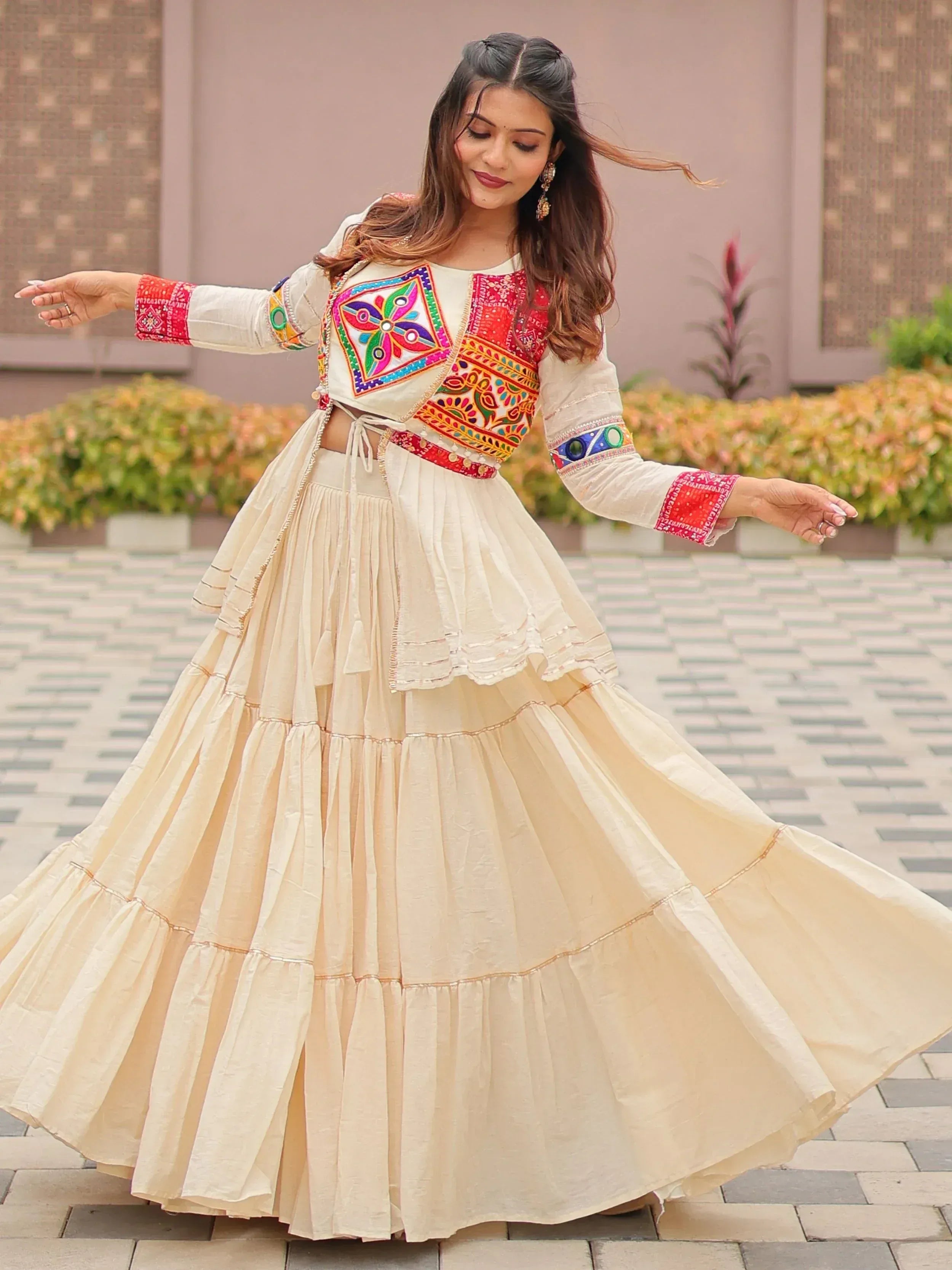 Woman twirling in cream ethnic lehenga with colorful embroidered blouse, perfect for festive occasions.