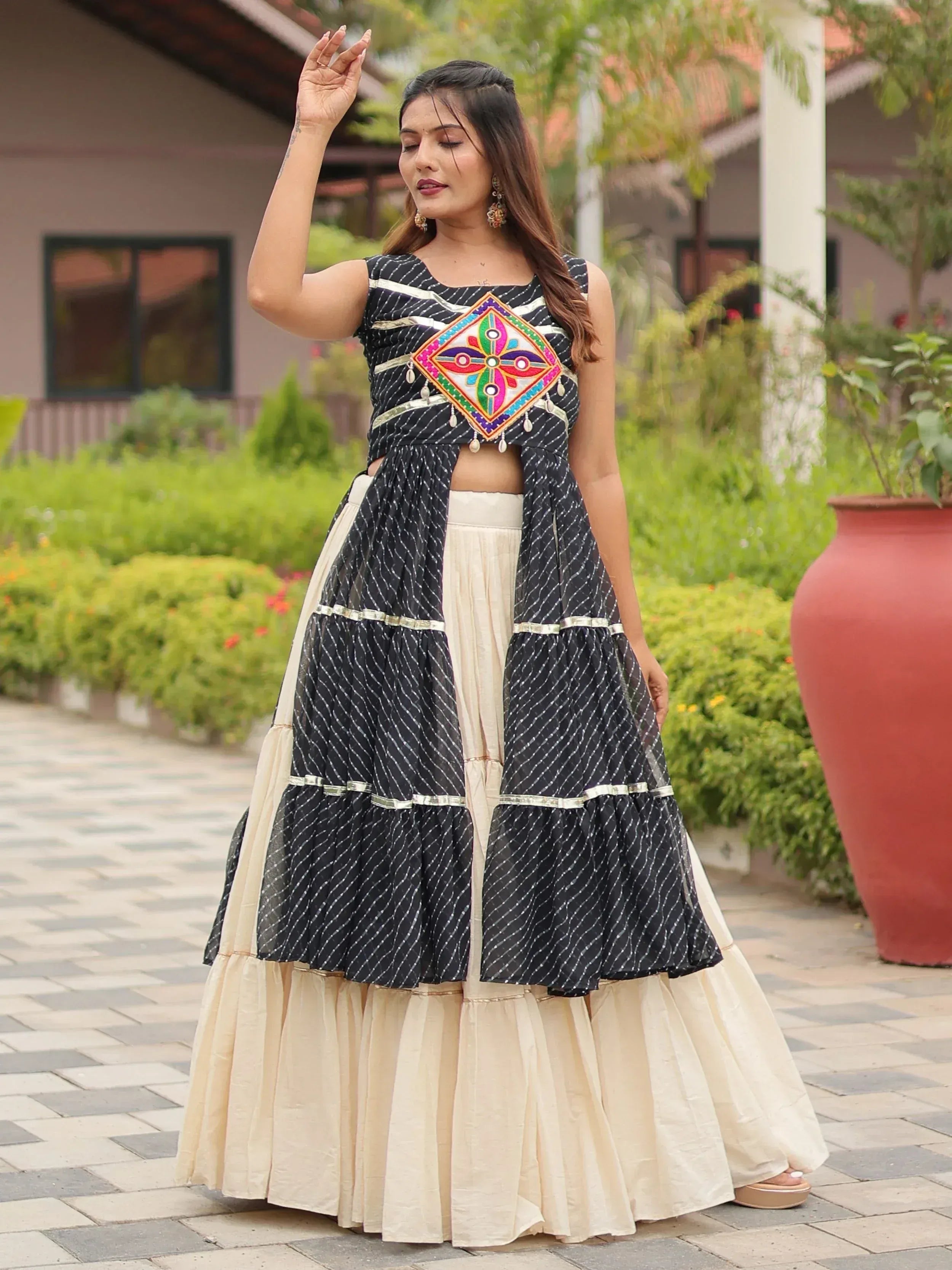 Black and cream ethnic lehenga choli with colorful mirror work and tiered skirt, perfect for Indian occasions.