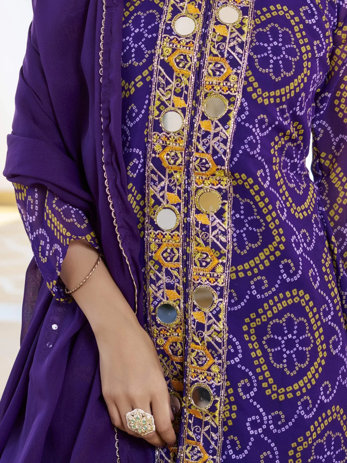 Purple ethnic gown with mirror embroidery and gold detailing, perfect for Indian festive wear.