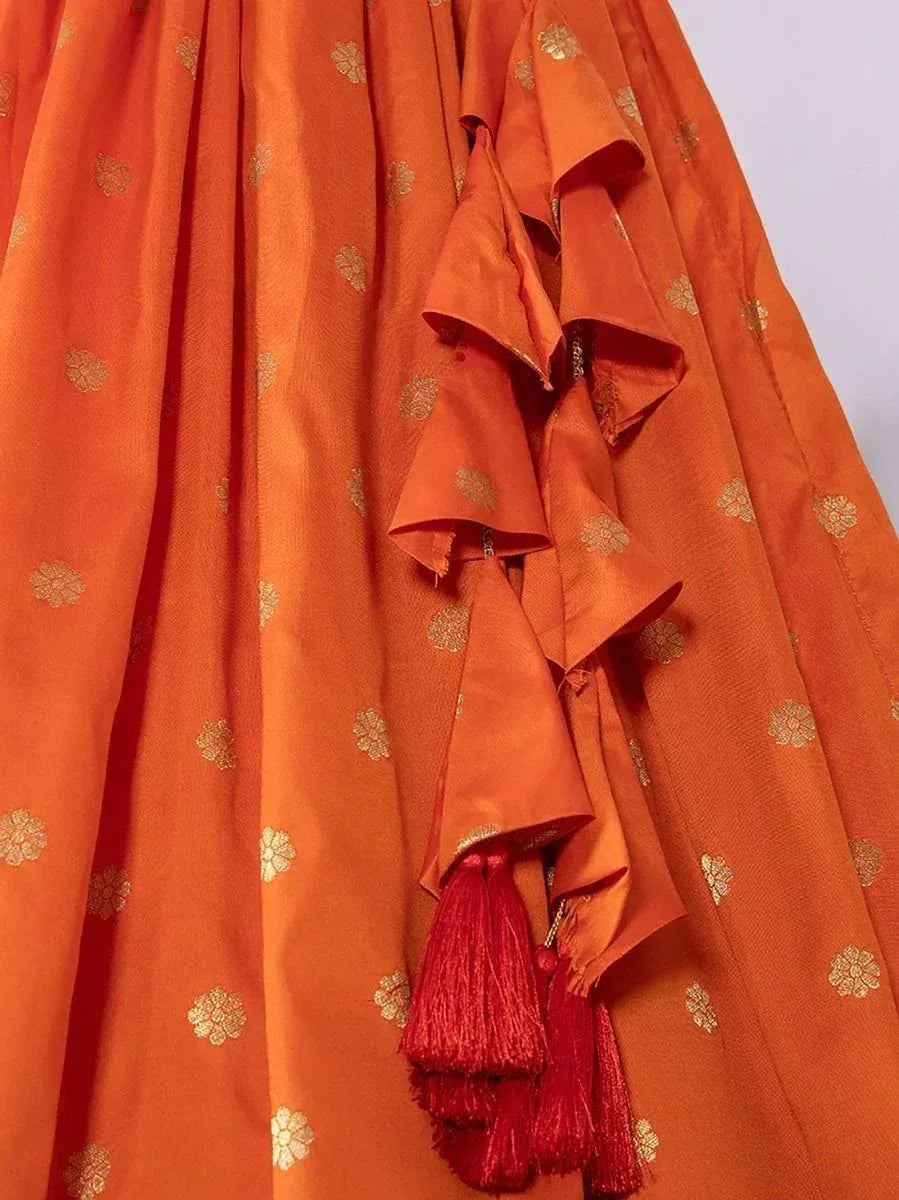 Orange ethnic lehenga with gold floral motifs and red tassels, perfect for Indian weddings and festive occasions.