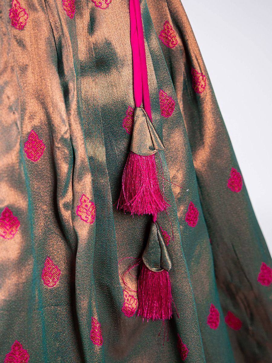 Green and gold ethnic lehenga with pink embroidery and tassels, perfect for Indian weddings and festivals.