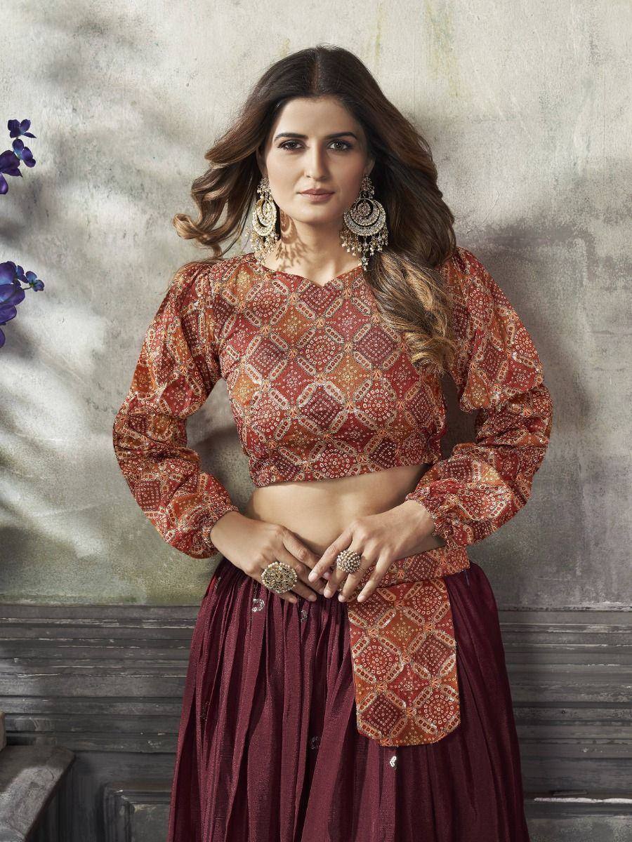 Woman in red printed crop top and maroon pleated skirt, ethnic Indian wear with statement jewelry