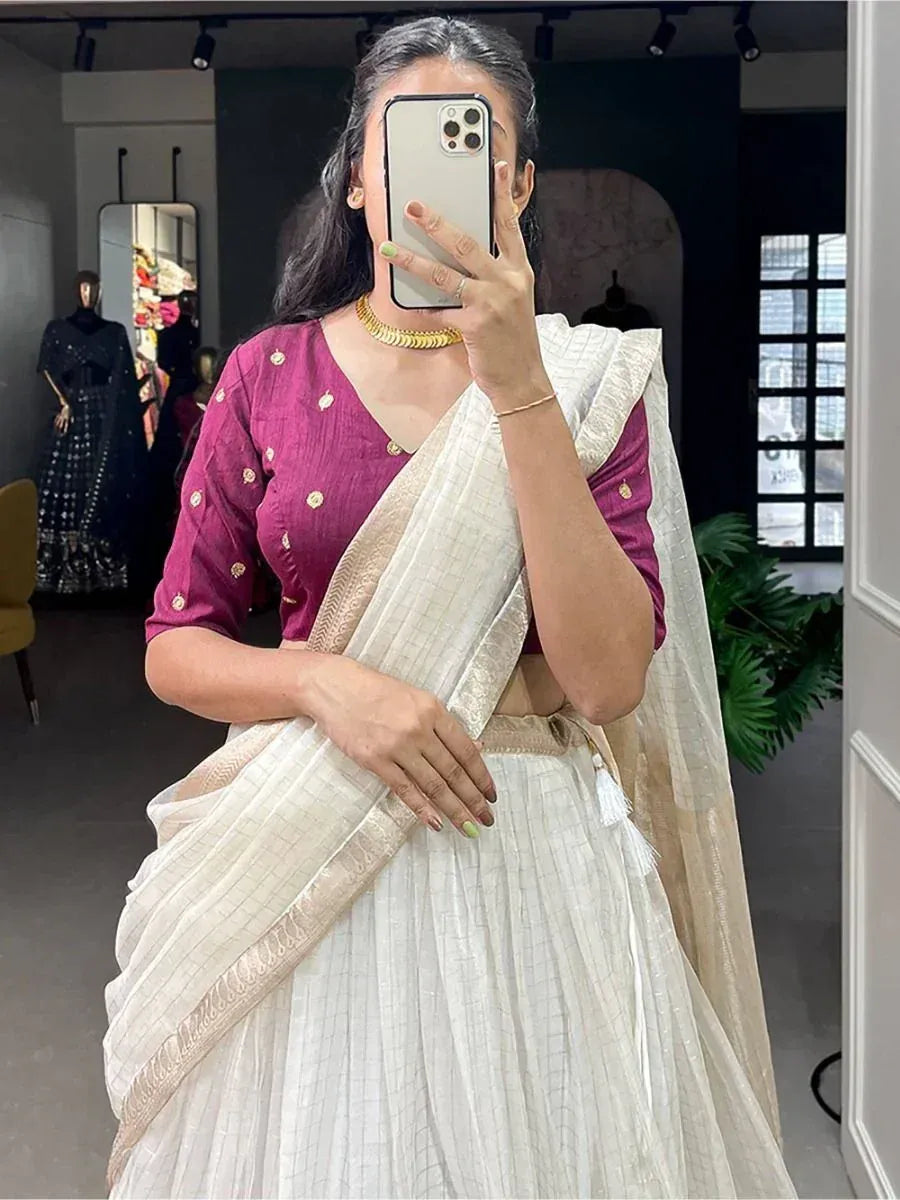Woman in white saree with maroon blouse, gold jewelry, taking mirror selfie in boutique