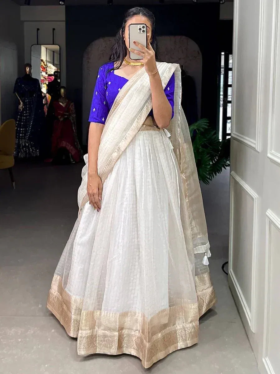 Woman in white lehenga with gold border and royal blue blouse, ethnic Indian wear