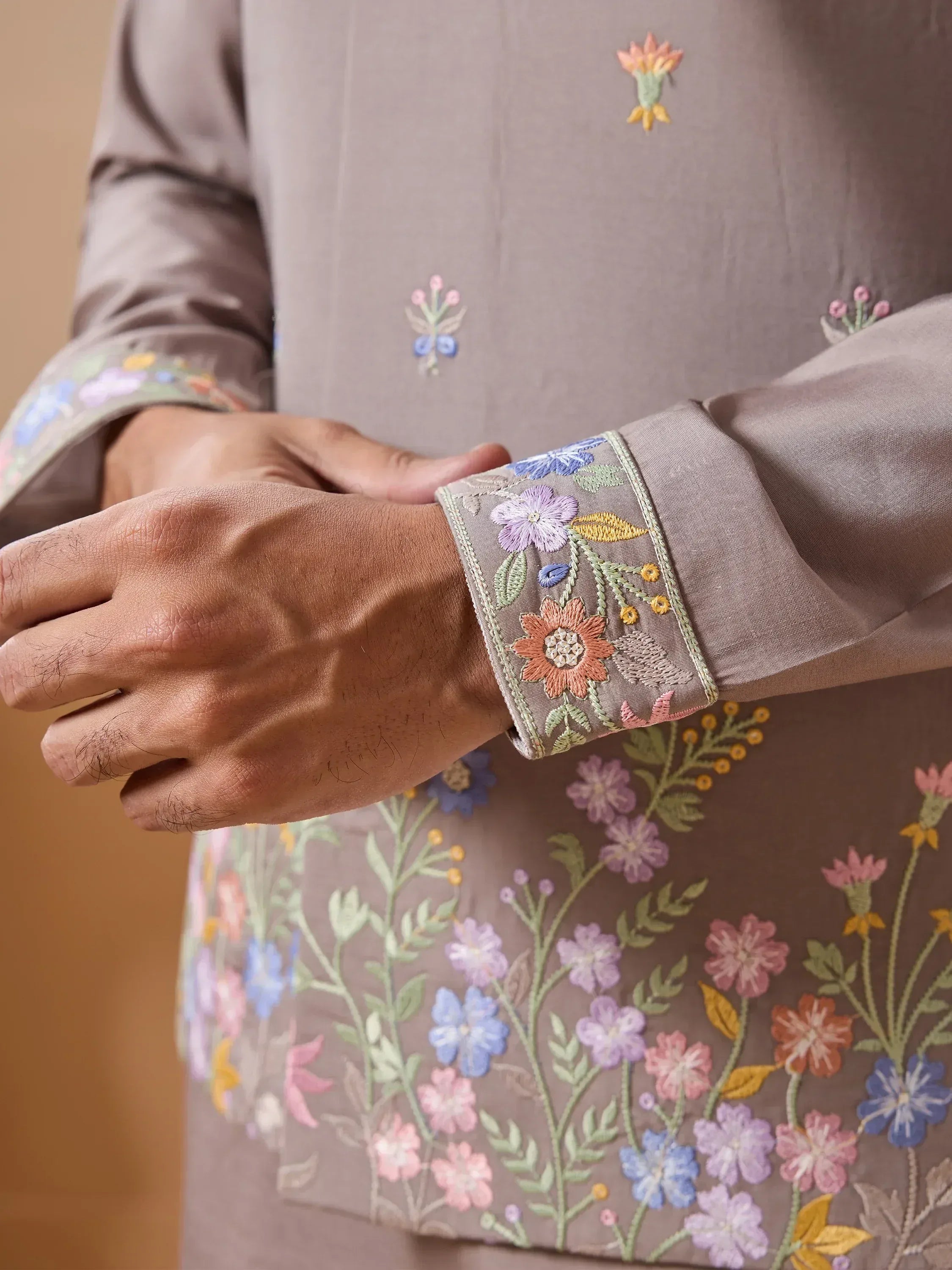 Embroidered floral cuff on Indian ethnic wear, showcasing vibrant floral designs on a muted background.