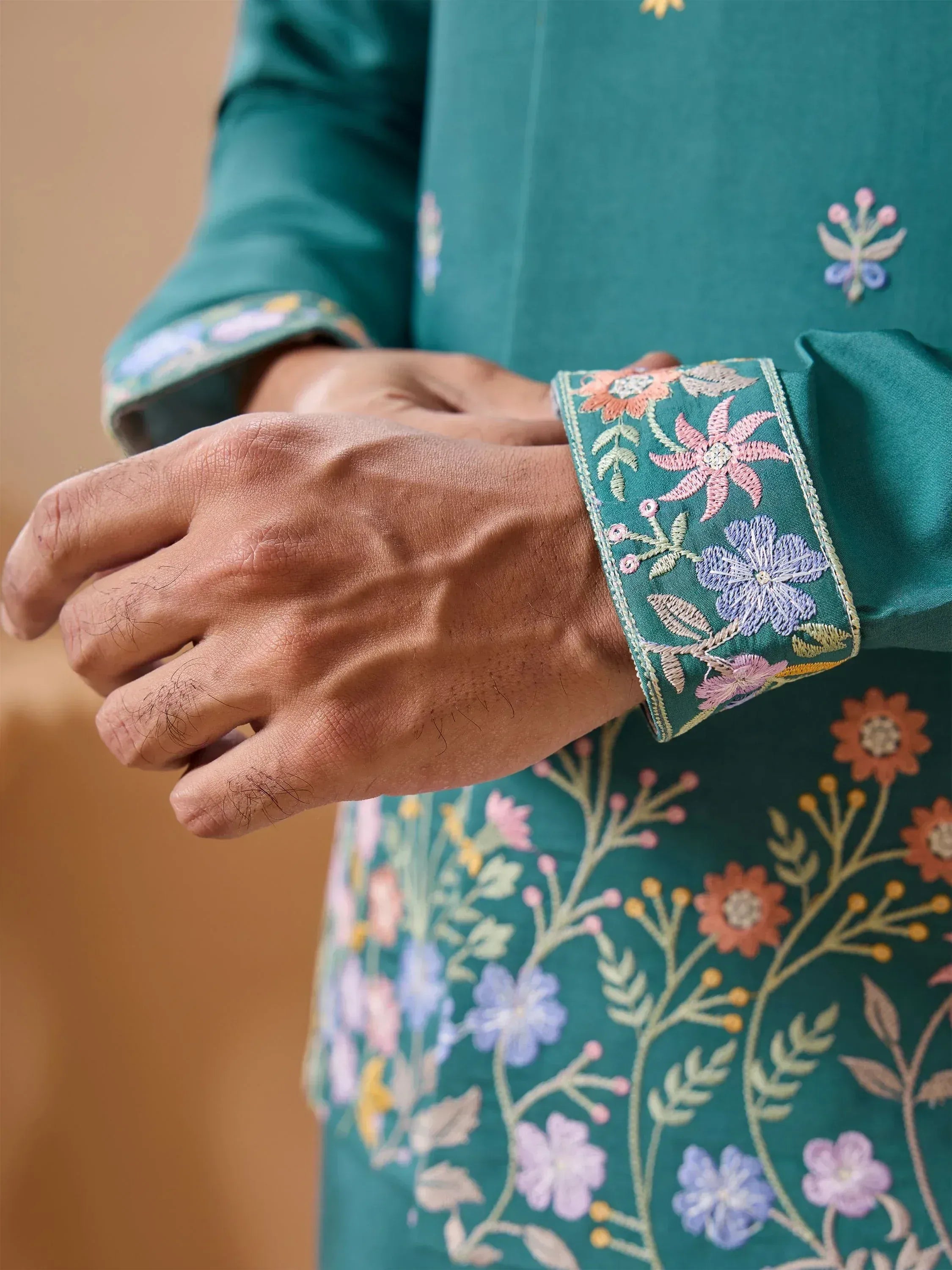 Teal kurta with intricate floral embroidery on cuffs and sleeves, showcasing detailed Indian ethnic wear design.