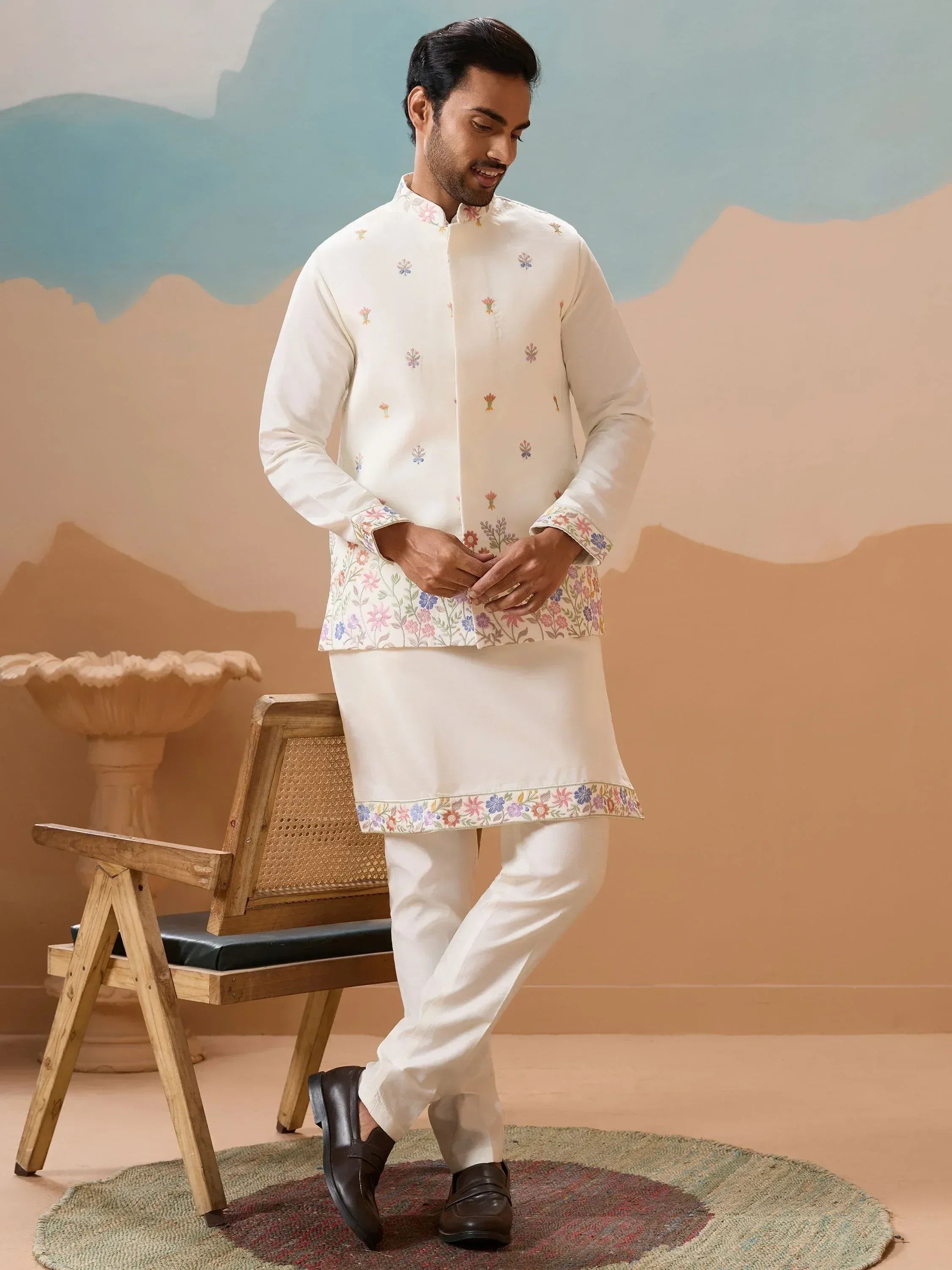 Man wearing white floral embroidered kurta with matching pants, ideal for ethnic occasions.