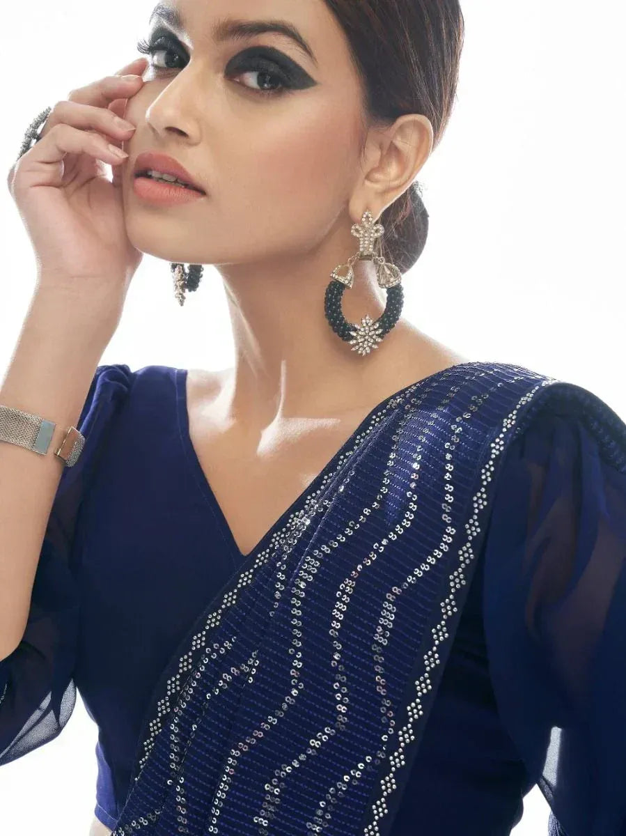 Navy blue sequin saree with sheer sleeves, statement earrings, and elegant ethnic wear styling