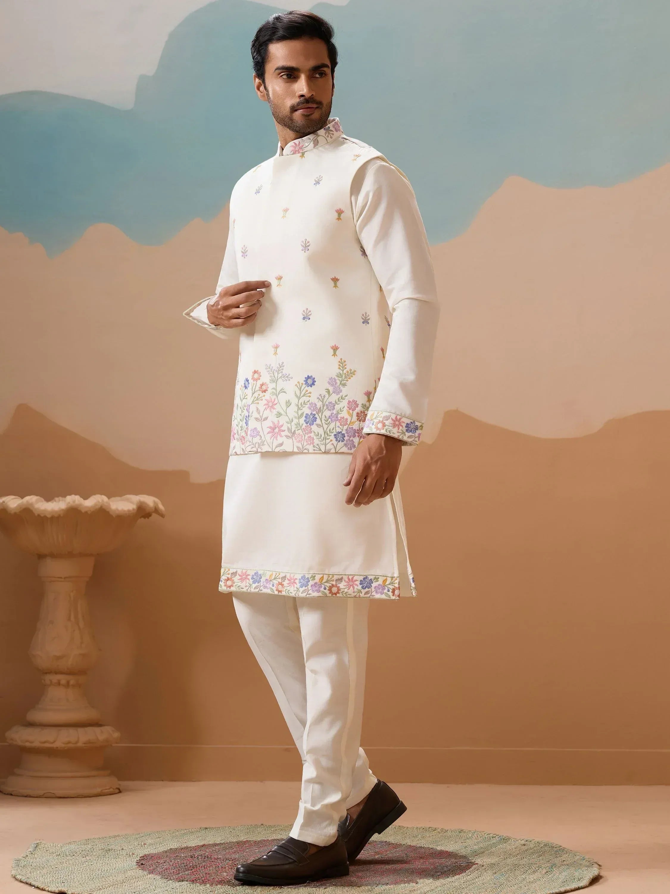 Man wearing white embroidered kurta set with floral designs, ideal for ethnic occasions.