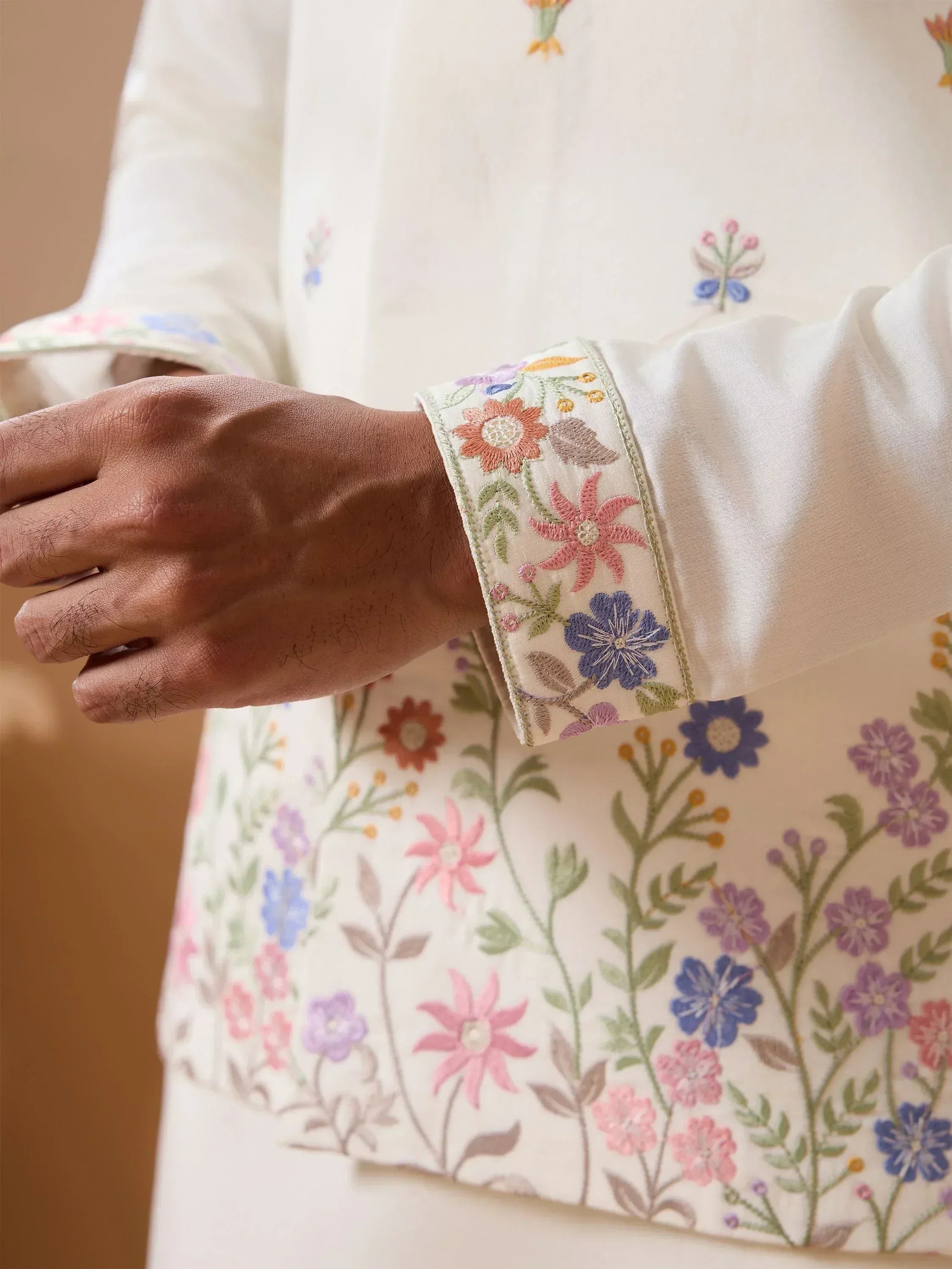 White ethnic kurta with colorful floral embroidery on sleeves and body, perfect for Indian wear.