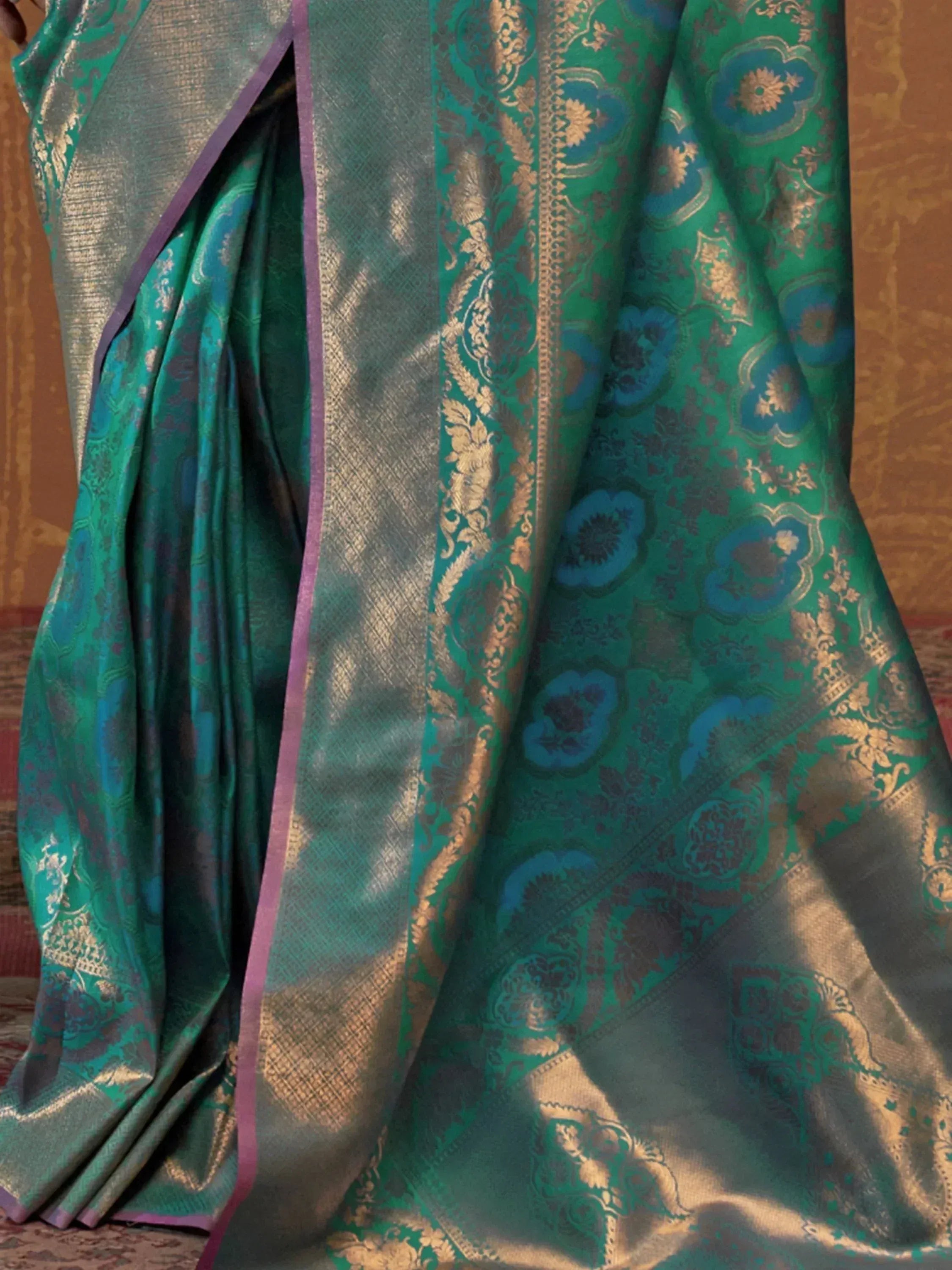 Emerald green designer saree with gold floral motifs and purple border, ideal for ethnic wear occasions.