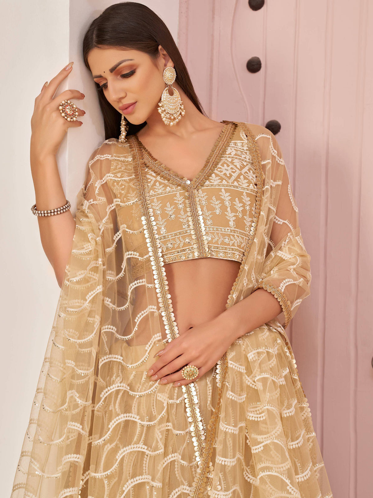 Elegant beige lehenga choli with intricate white embroidery and gold sequin detailing, perfect for Indian ethnic wear.