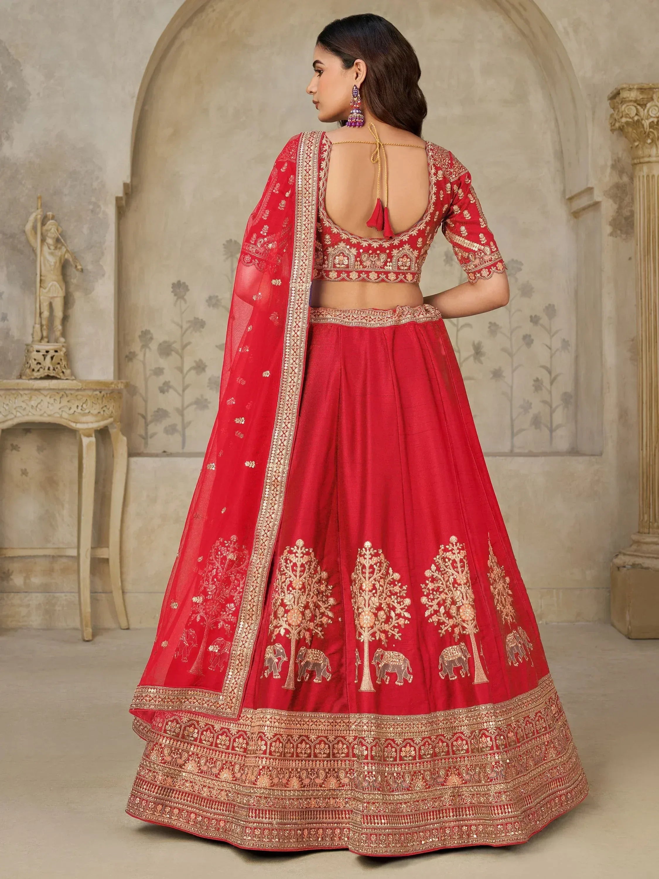 Red designer lehenga choli with gold embroidery, elephant motifs, and sheer dupatta for Indian ethnic wear