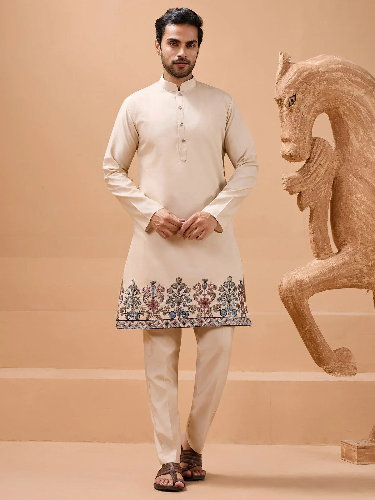Men's cream kurta with floral embroidery, paired with matching churidar pants for ethnic wear.