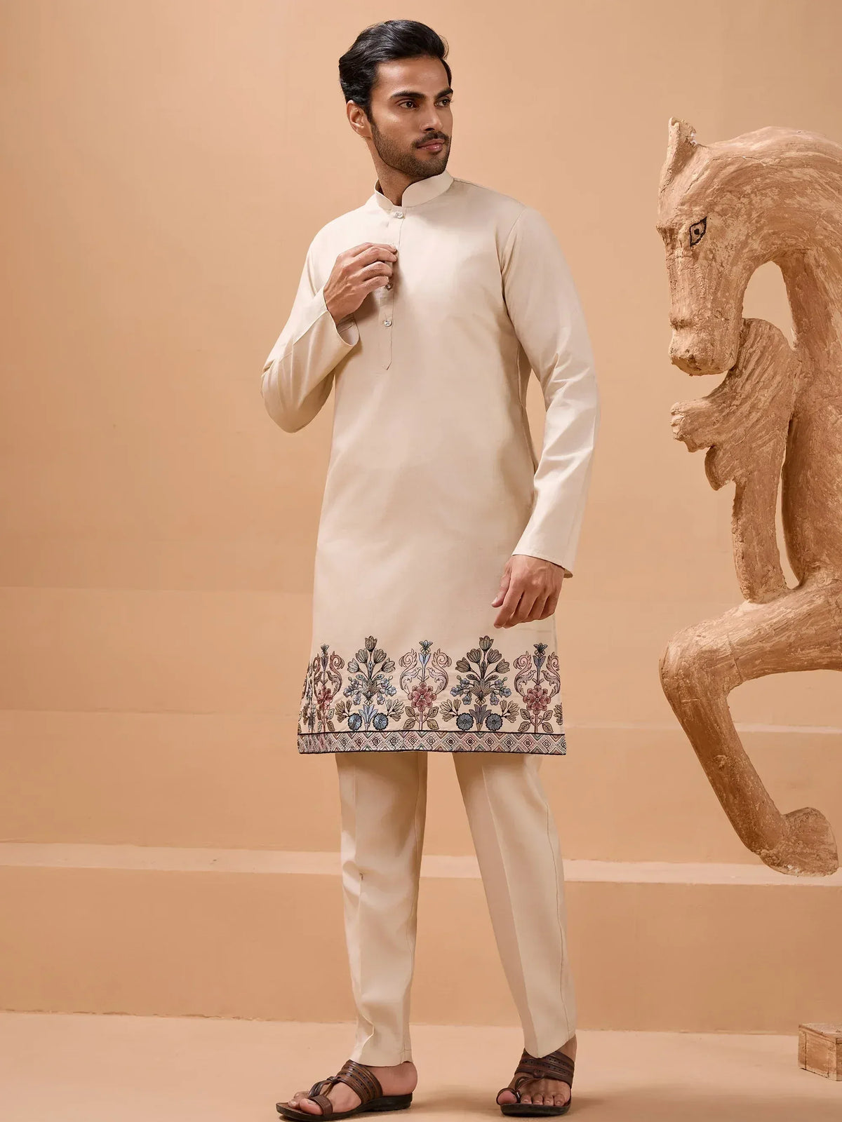 Men's cream kurta with floral embroidery, paired with matching churidar pants for ethnic wear.