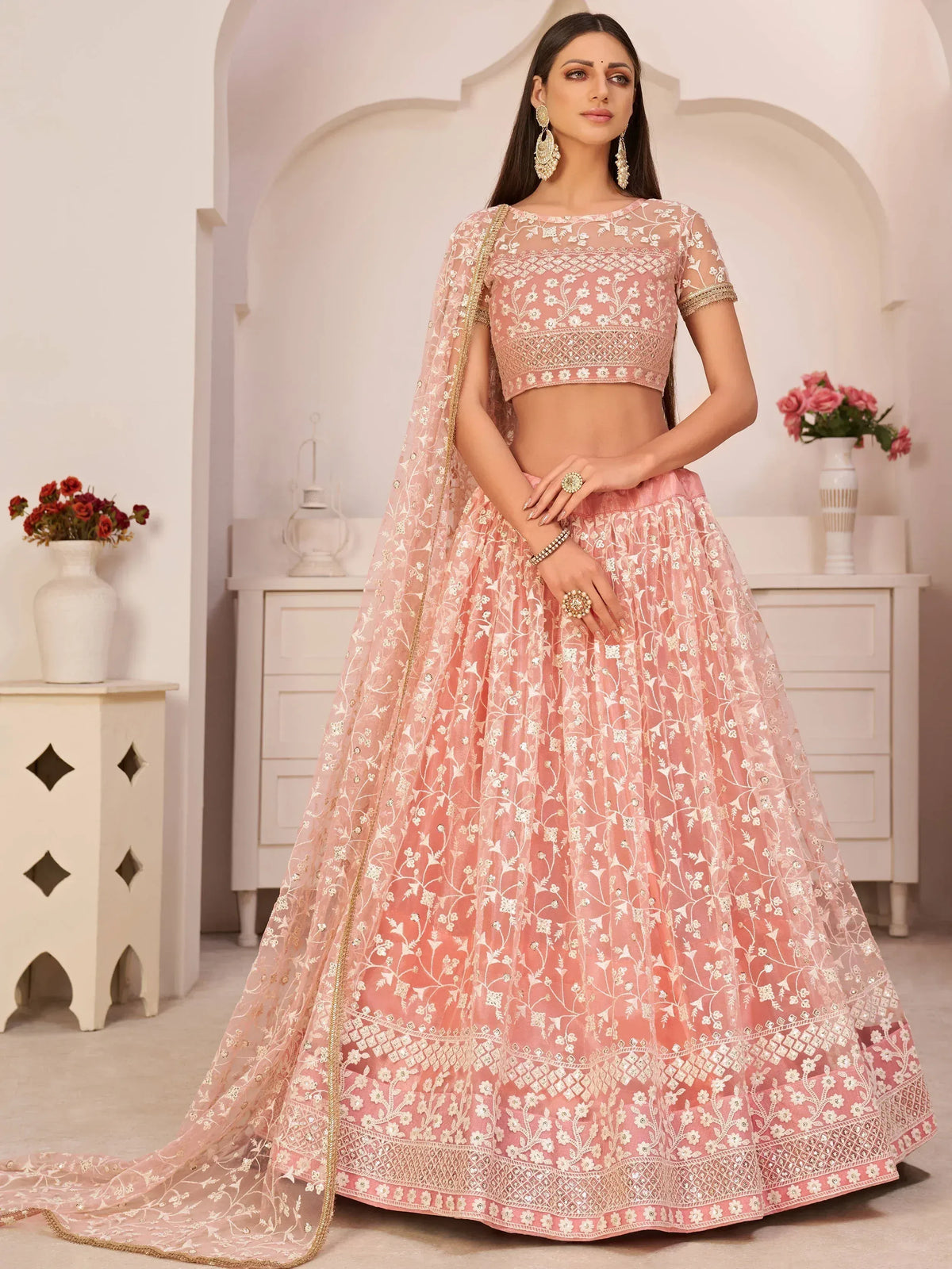 Pink embroidered lehenga choli with floral motifs and gold trim, perfect for Indian weddings or festive occasions.