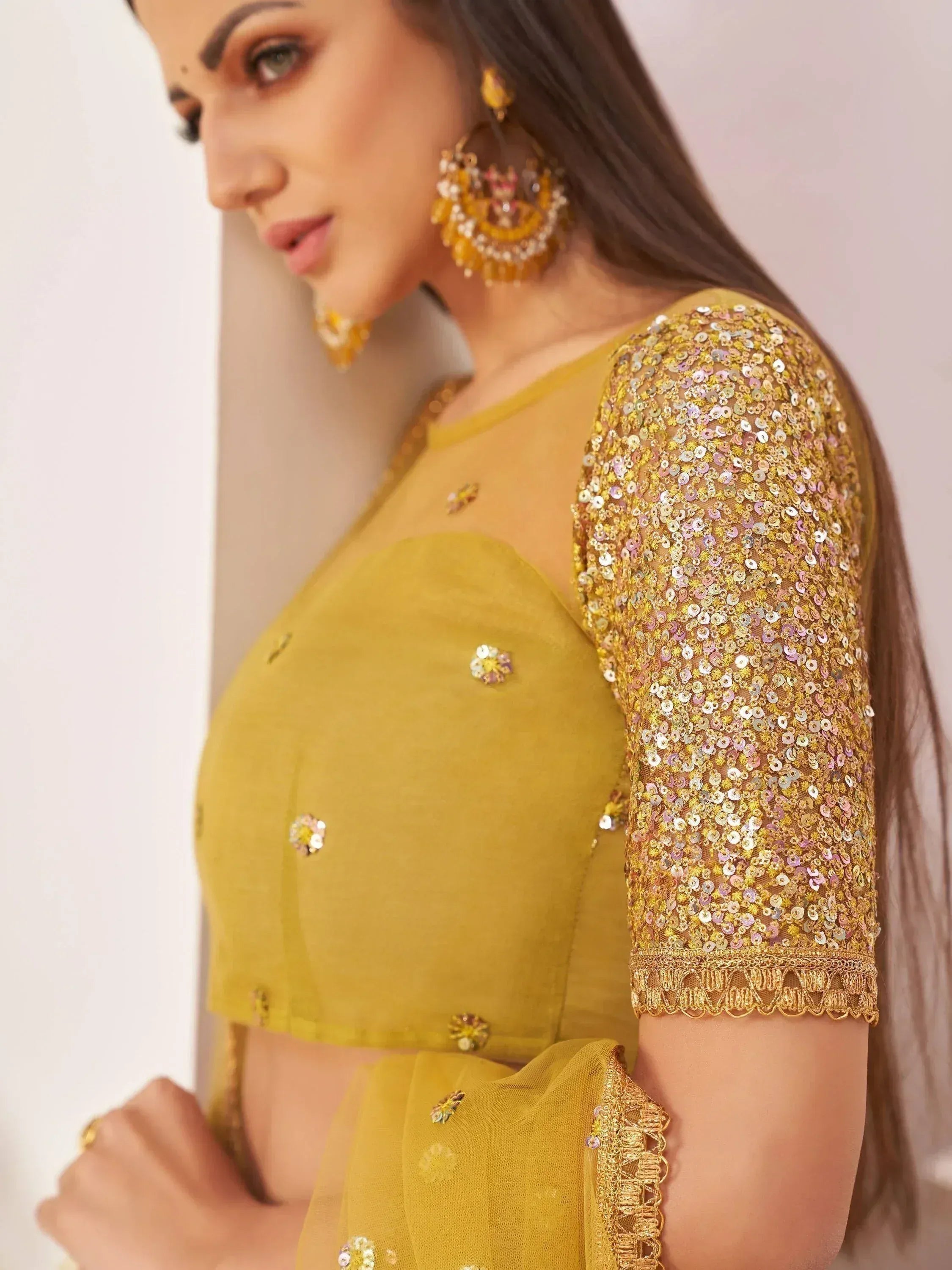 Mustard yellow ethnic blouse with sequin sleeves and floral embroidery, paired with statement earrings.