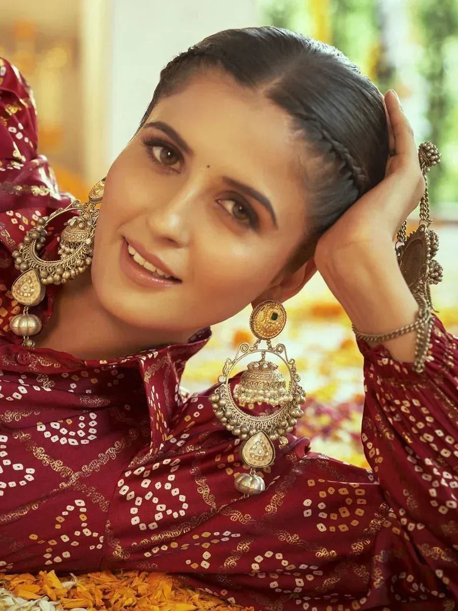 Woman in maroon ethnic blouse with gold embroidery and traditional jhumka earrings, styled for Indian festive wear