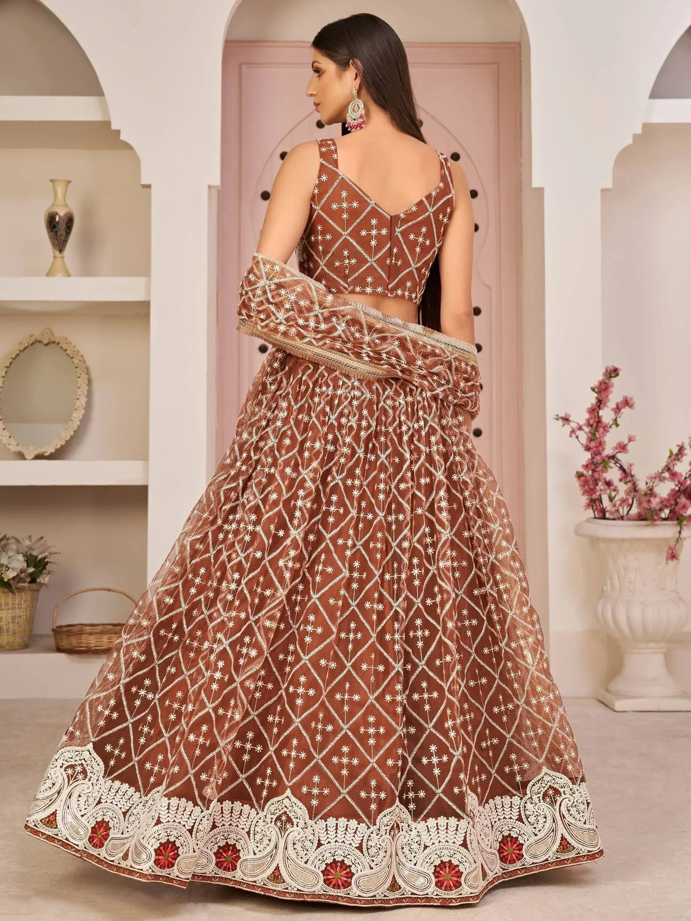 Brown embroidered lehenga choli with white floral patterns and lace border, perfect for Indian ethnic occasions.