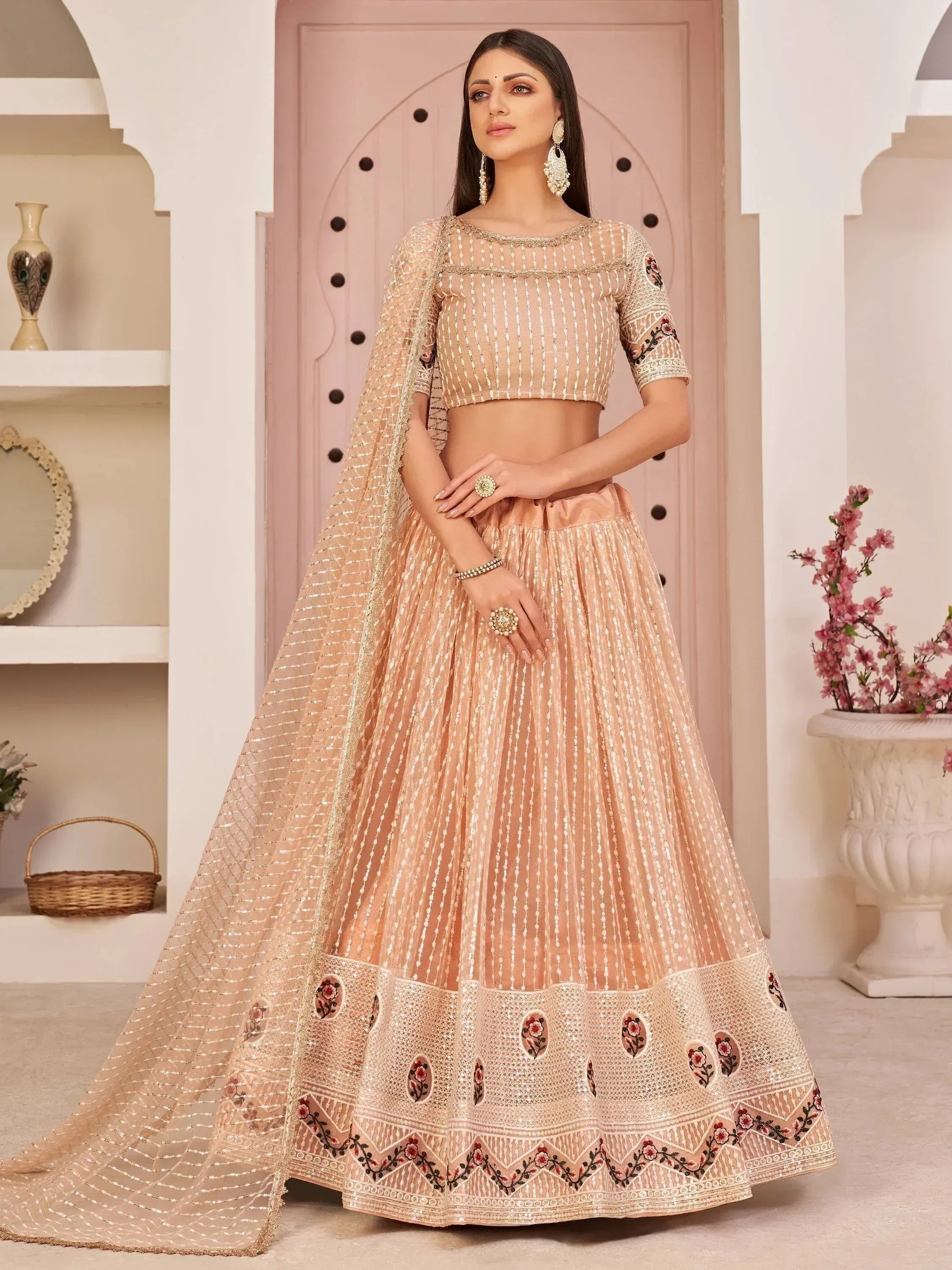 Elegant peach lehenga choli with floral embroidery and sheer dupatta, perfect for Indian weddings and festive occasions.