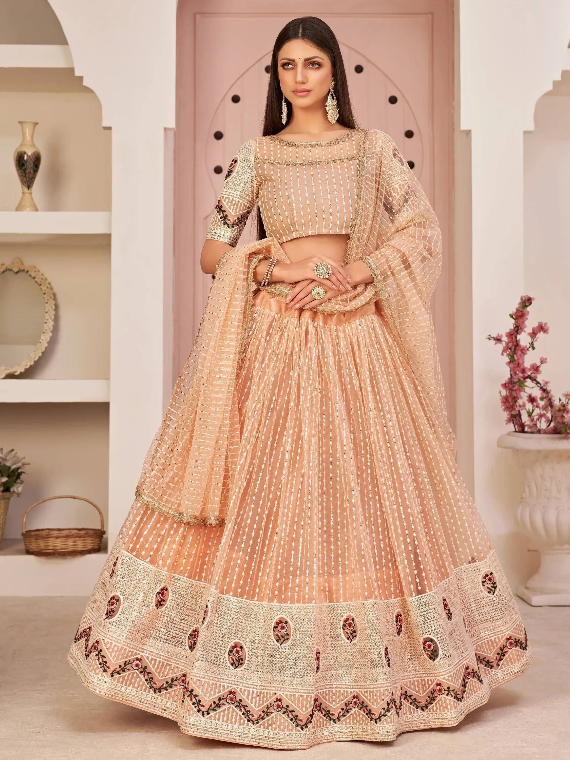 Elegant peach lehenga choli with floral embroidery and sheer dupatta, perfect for Indian weddings and festive occasions.