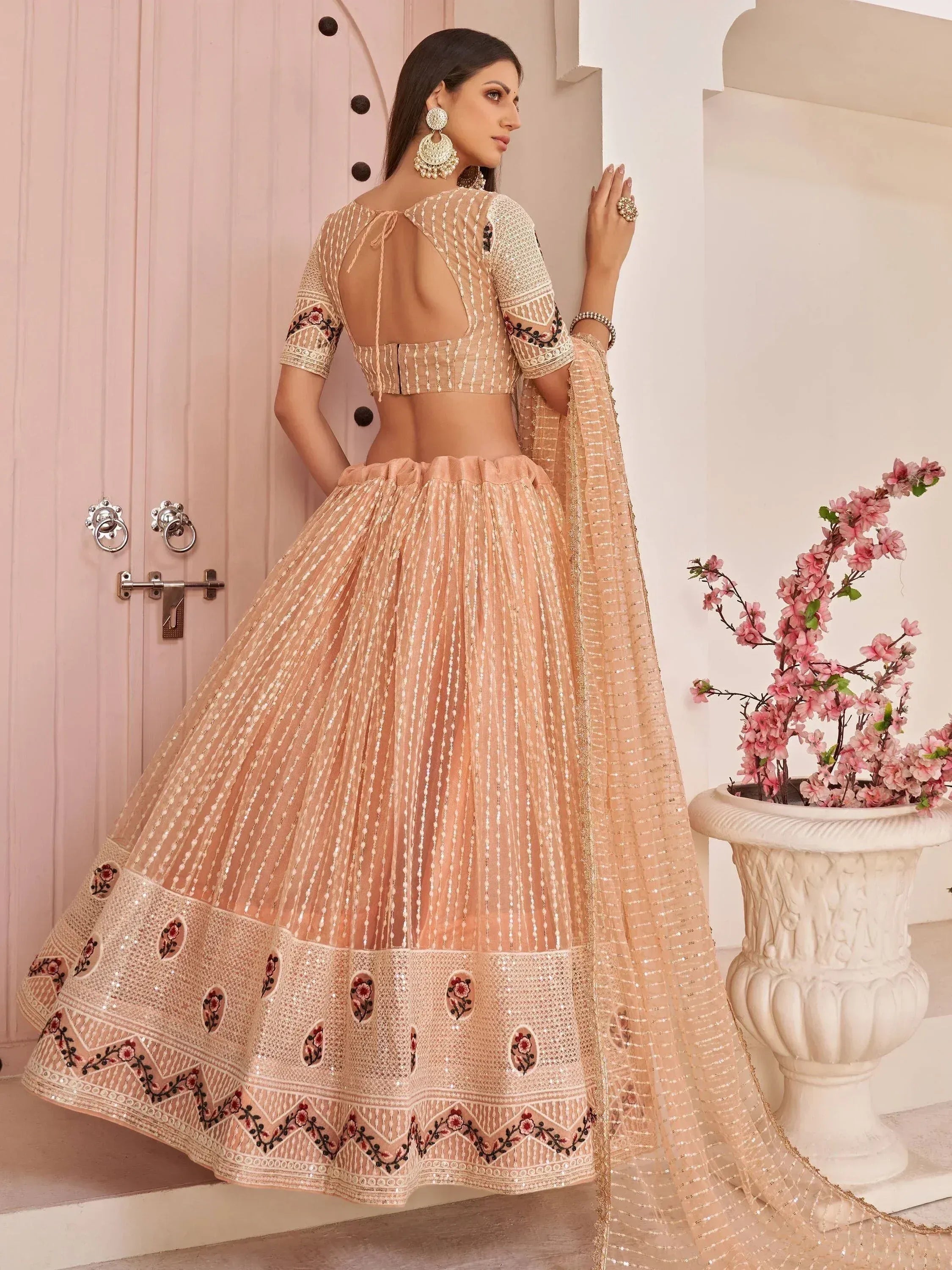 Elegant peach lehenga choli with floral embroidery, sequins, and back tie detail, perfect for Indian weddings or festive occasions.