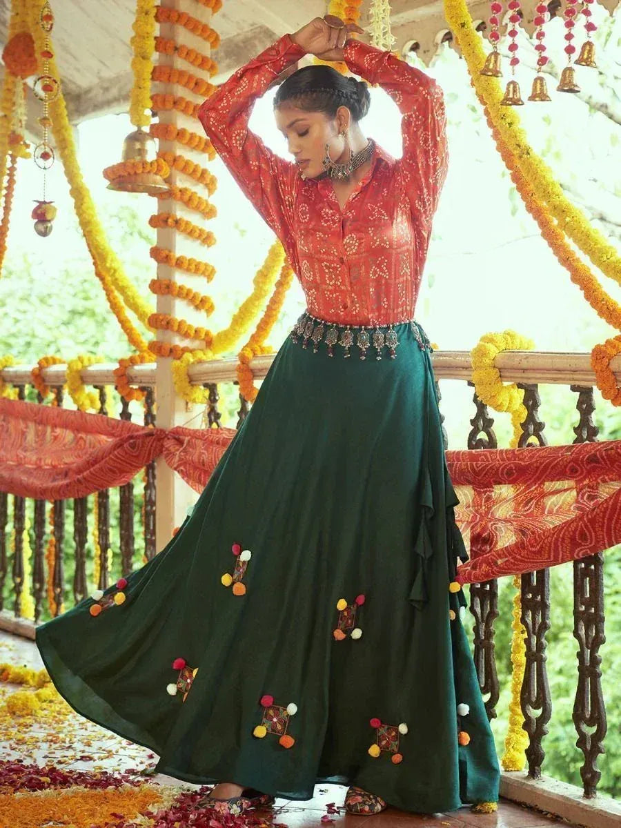 Woman in red embroidered top and green floral skirt, festive Indian ethnic wear with marigold decorations
