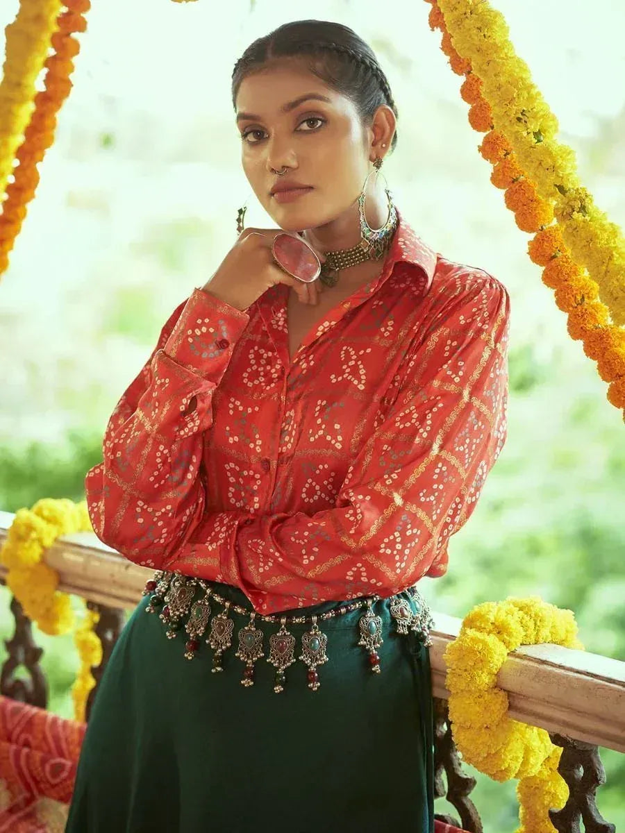 Woman in red printed blouse and green skirt with ethnic jewelry, marigold garlands