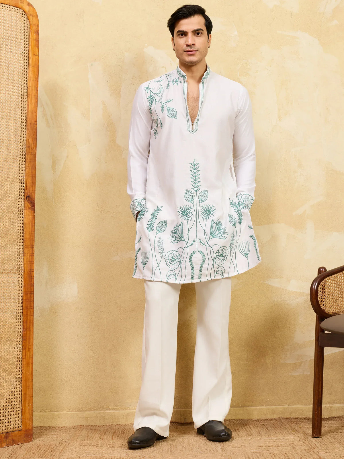 Man wearing a white designer kurta with blue floral embroidery and matching trousers