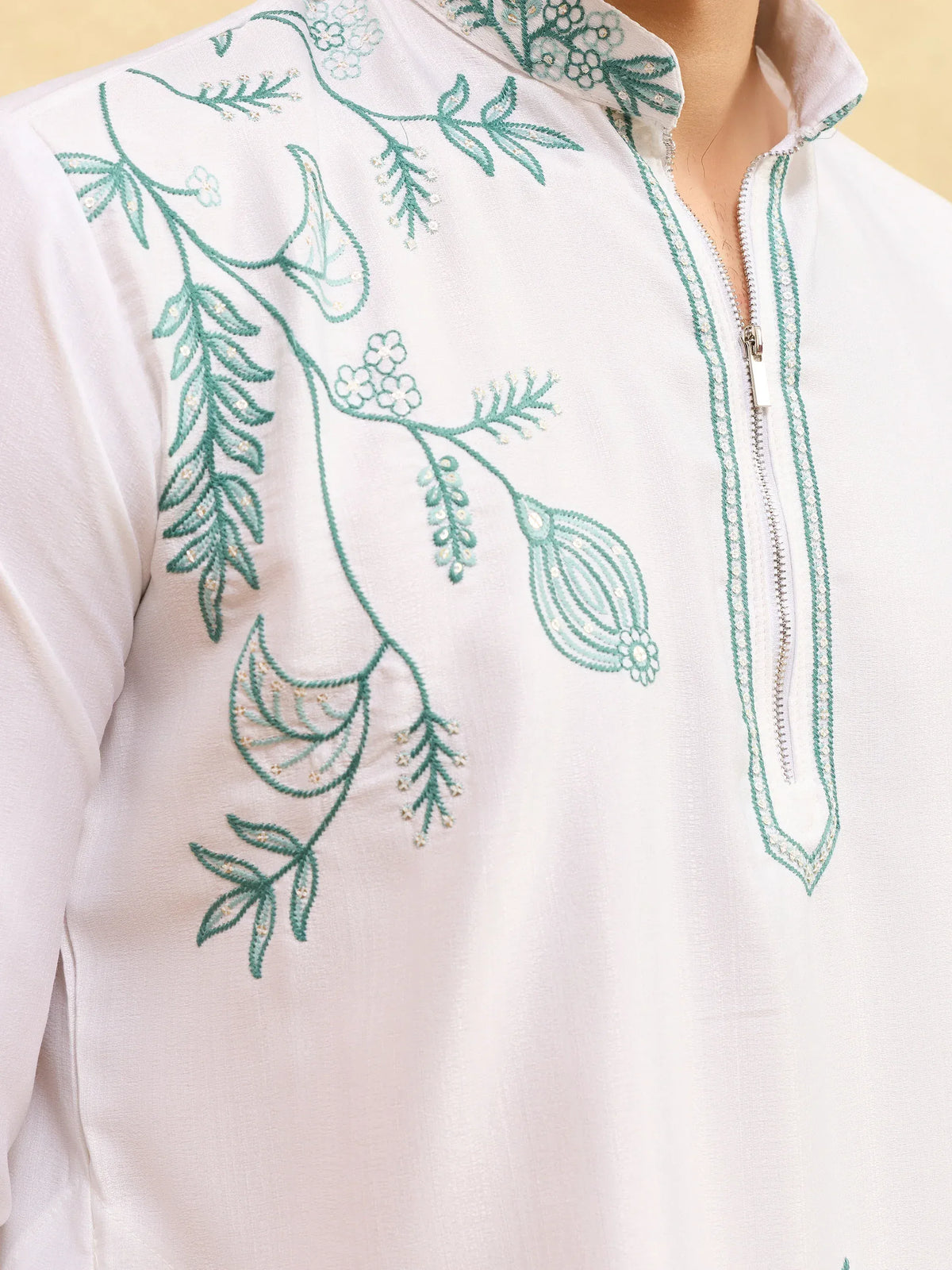 Close-up of a white Indian ethnic kurta with green floral embroidery and zipper neckline