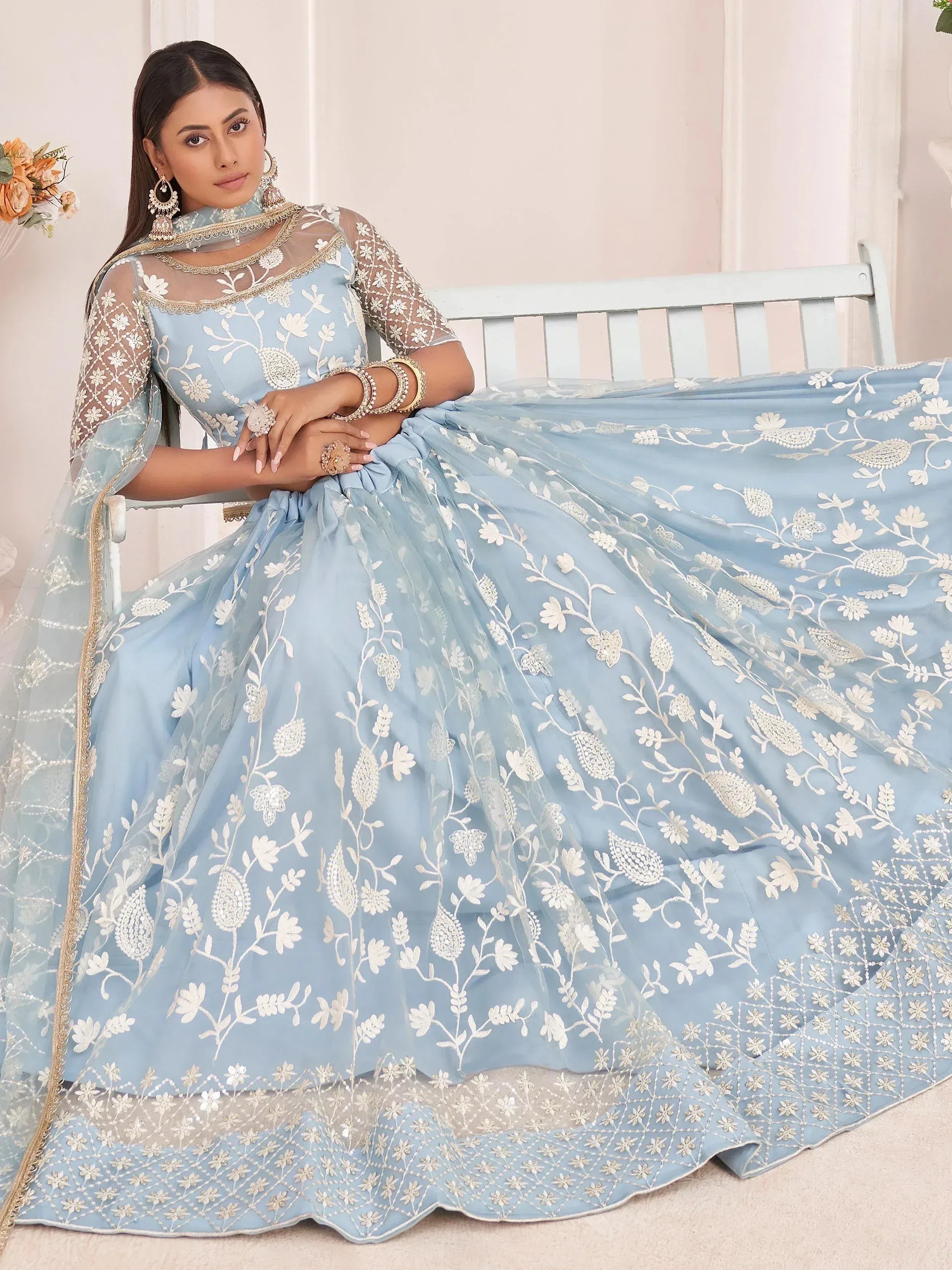 Light blue designer lehenga choli with white floral embroidery and sheer sleeves, perfect for Indian weddings or festive occasions.