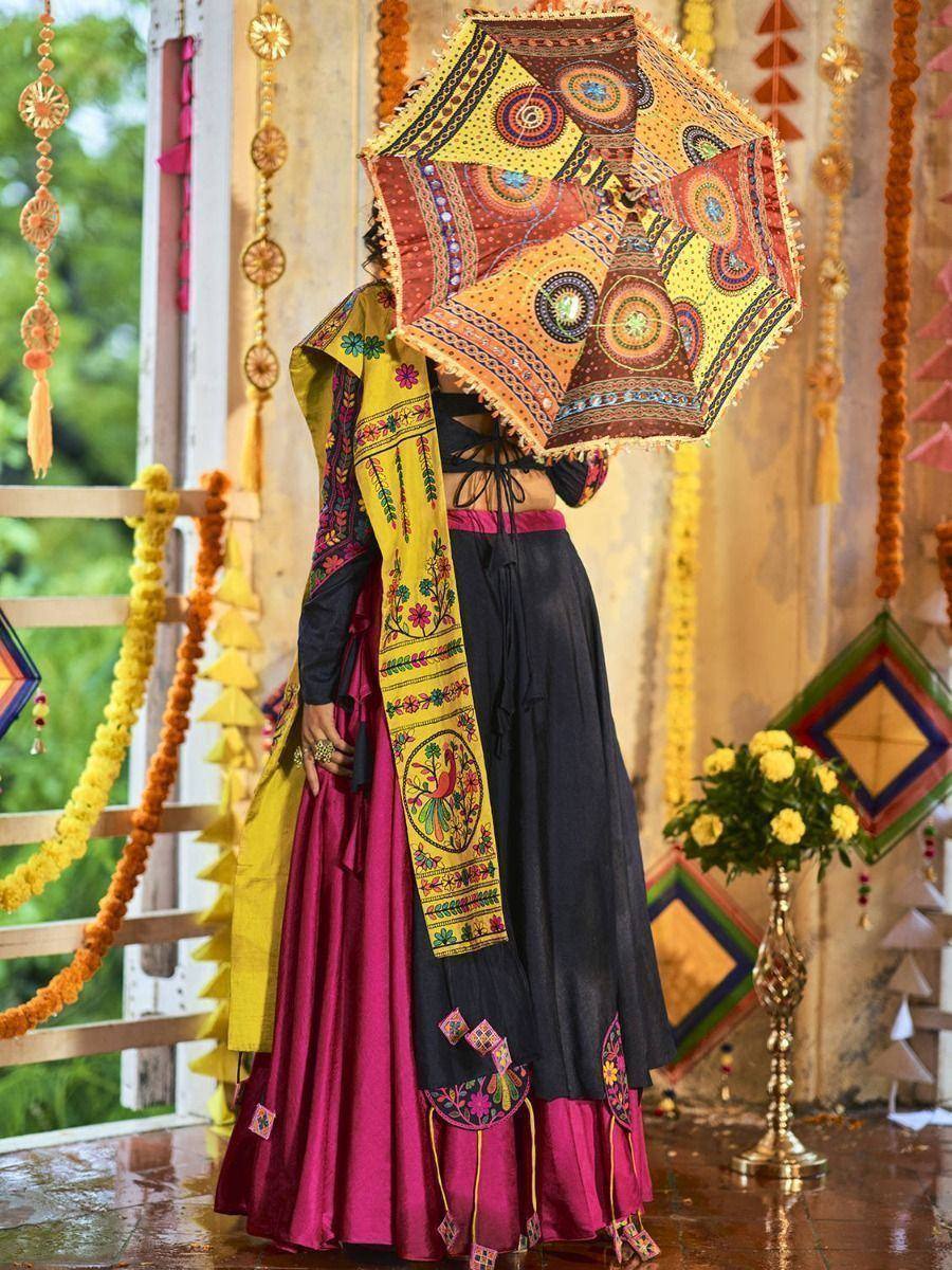 Woman in colorful embroidered Indian ethnic wear with patterned umbrella, festive decor