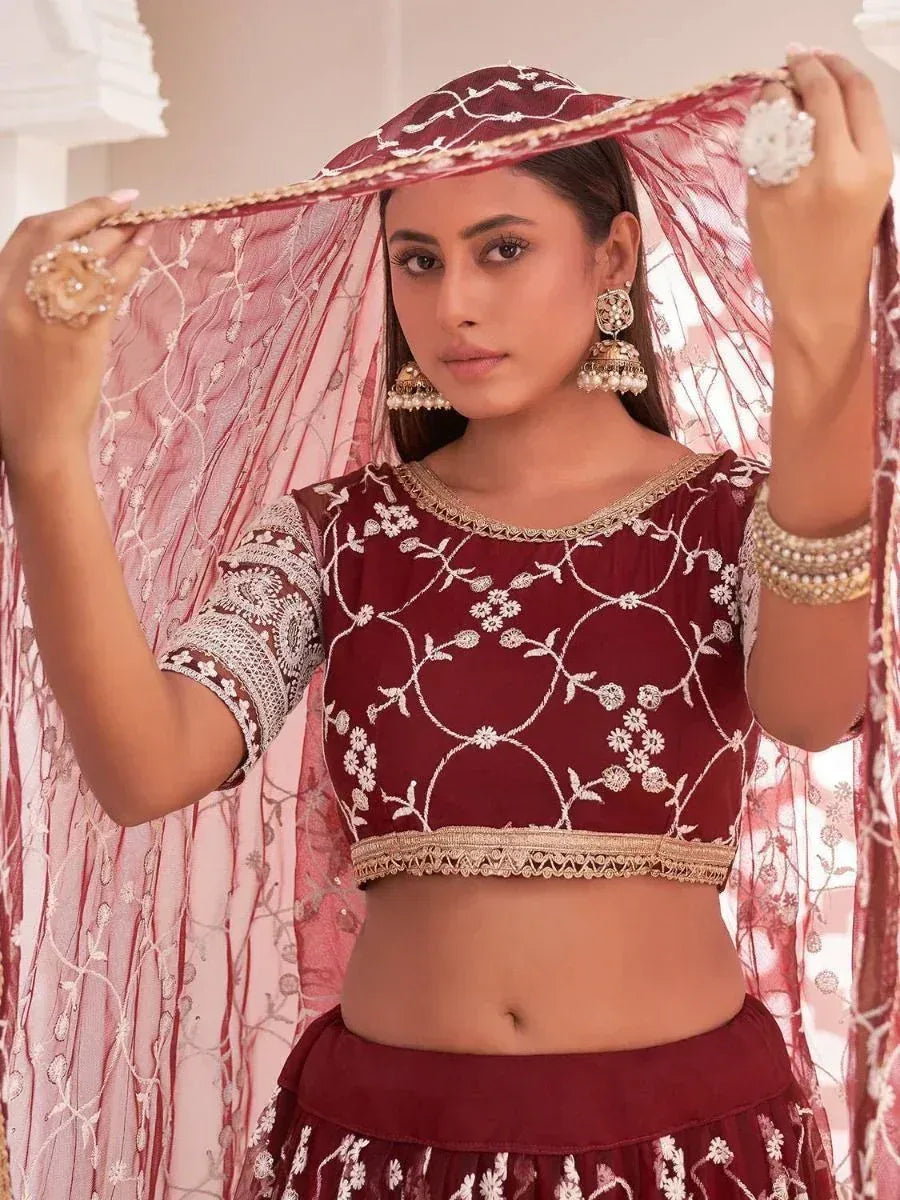Maroon embroidered lehenga choli with floral motifs and sheer dupatta, styled with jhumka earrings