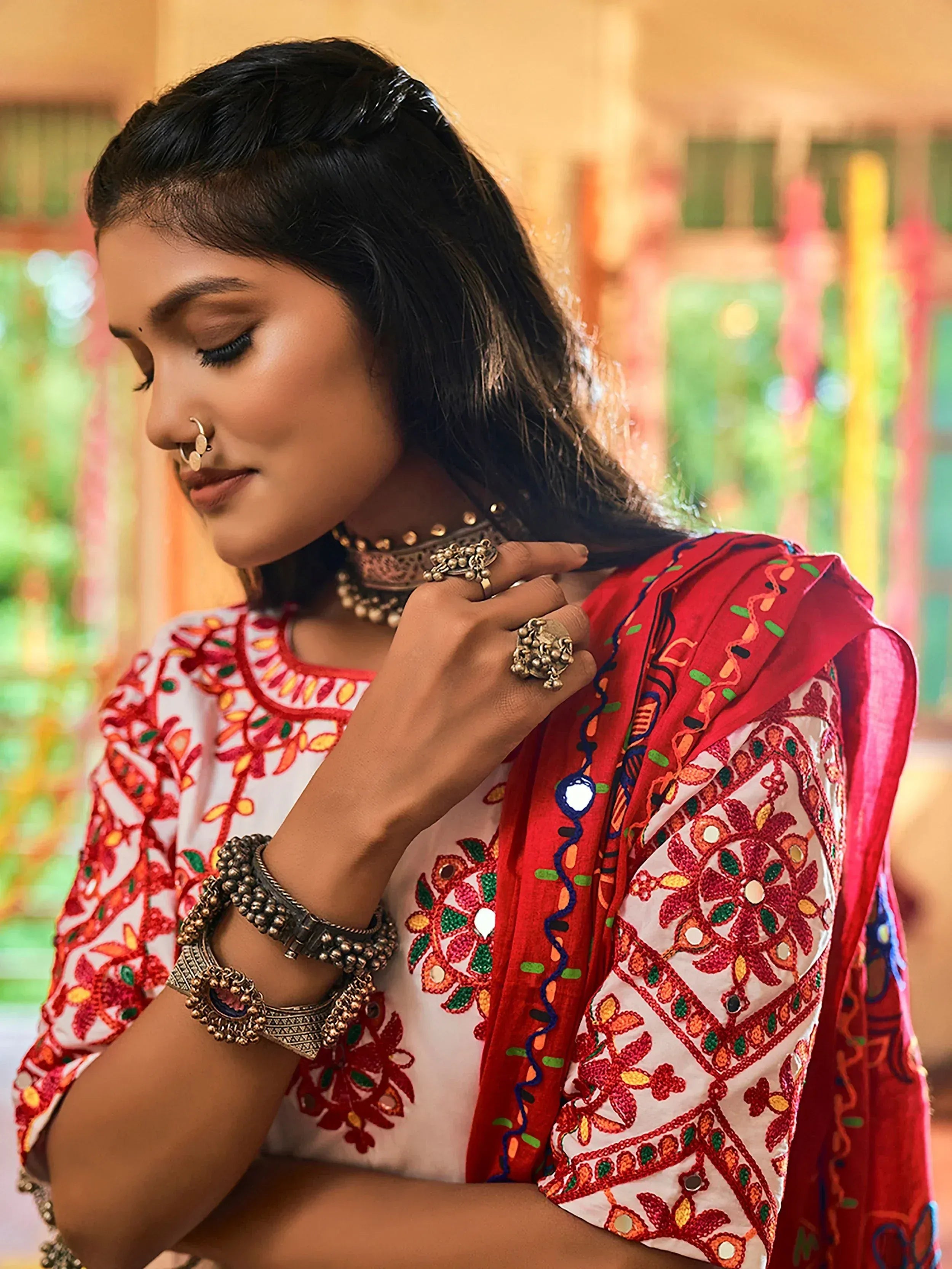 Woman in embroidered Indian ethnic wear with mirror work, red dupatta, and traditional jewelry